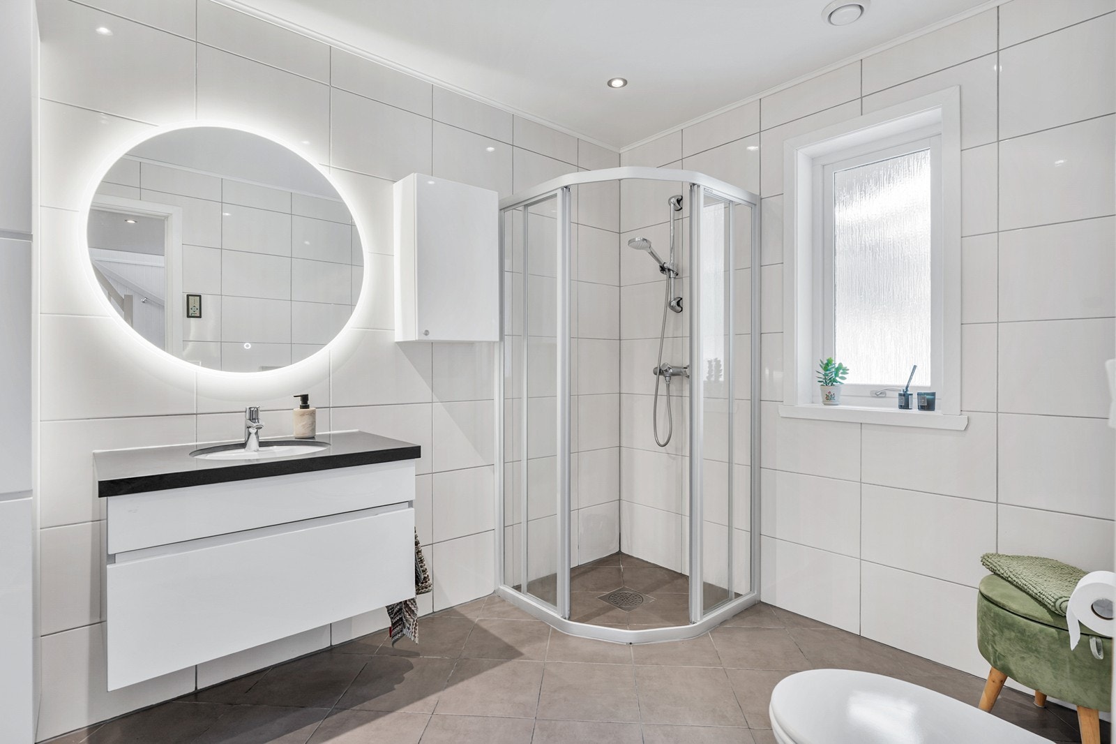 Moderne og nydelig helfliset bad som er innredet med vegghengt toalett, dusjhjørne og baderomsmøblement. Galleribilde