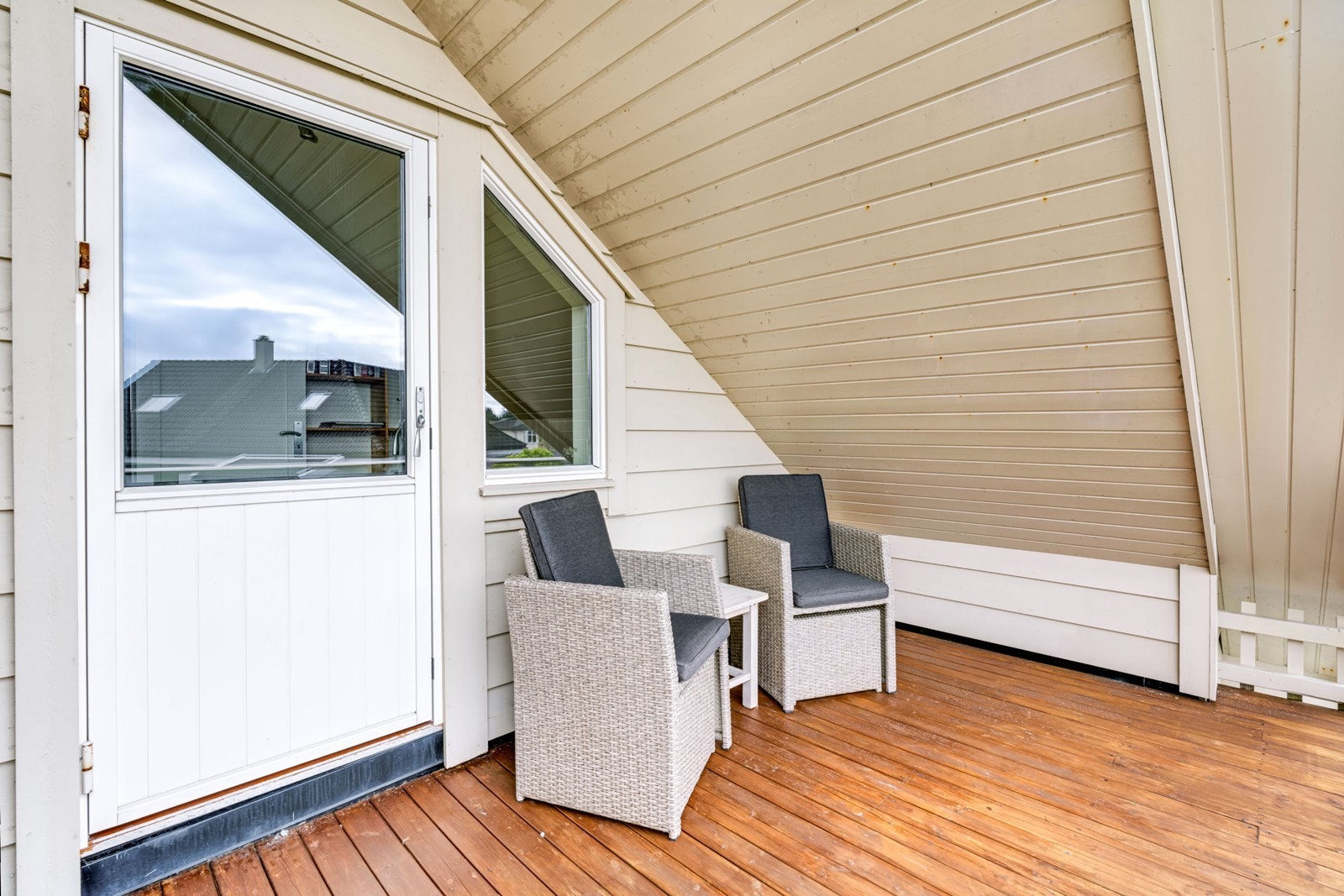 Overbygd balkong i andre etasje med terrassebord og rekkverk i tre. Galleribilde