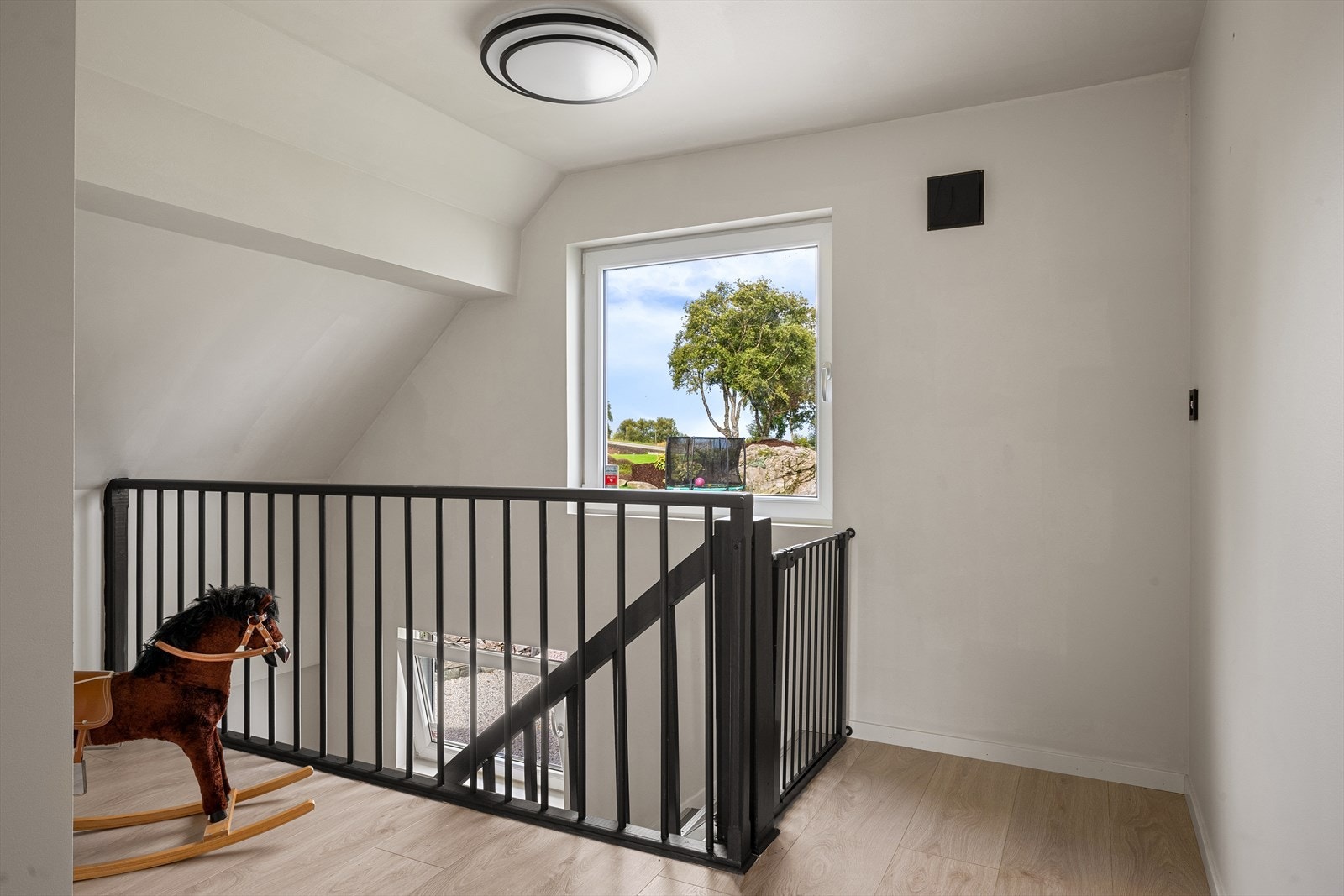 Trappegangen på loftet har vindu mot hagen og laminat på gulvet. Galleribilde