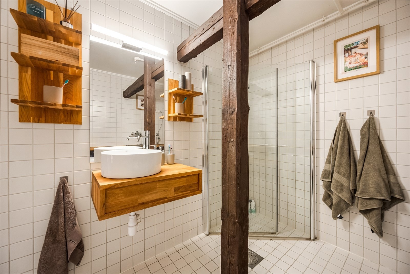 Badet er innredet med vegghengt toalett, dusjhjørne med svingbare glassdører og vegghengt servantinnredning. Galleribilde