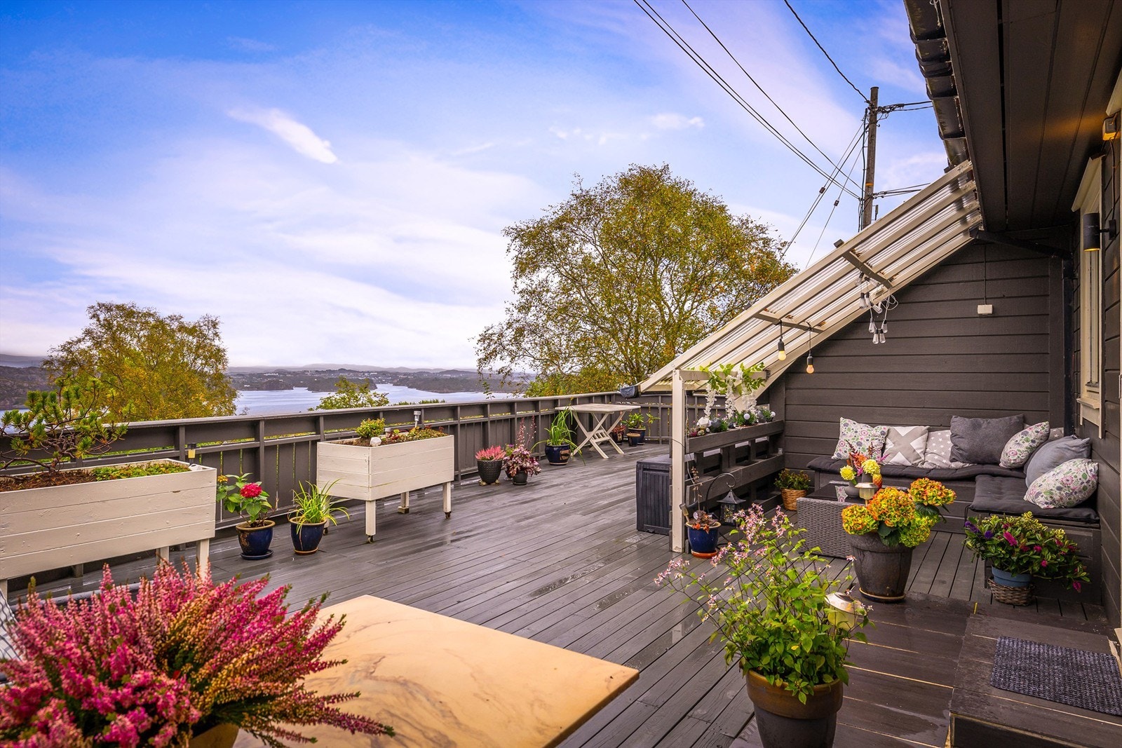 Stor treterrasse med overbygd sittegruppe og vidstrakt utsikt mot fjorden. Galleribilde