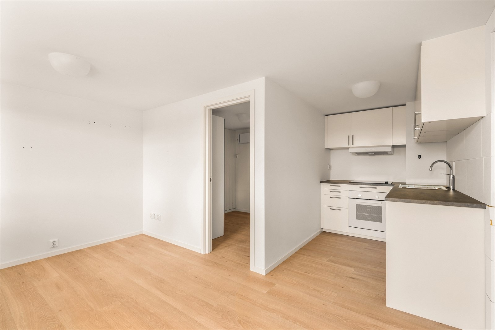Kjøkkeninnredning med laminert benkeplate, nedfelt stålvask, glatte fronter og opplegg for oppvaskmaskin. Galleribilde