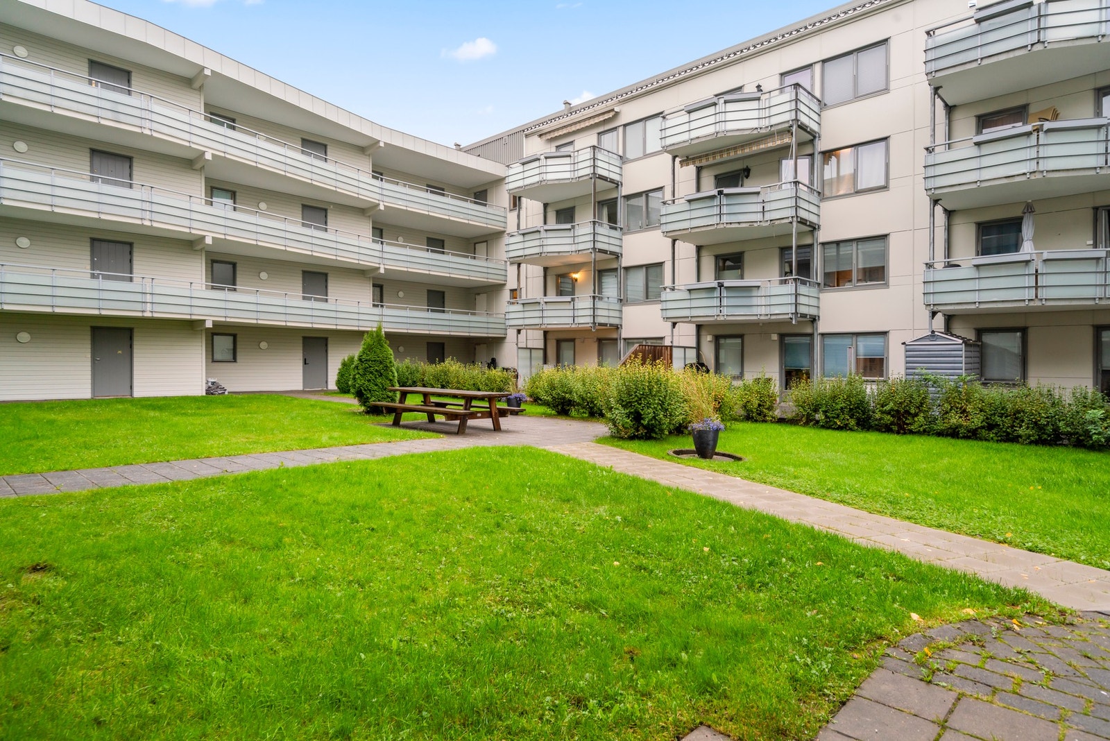 Pent opparbeidet fellesområde med grønne plenarealer, beplantning og sittegruppe. Galleribilde