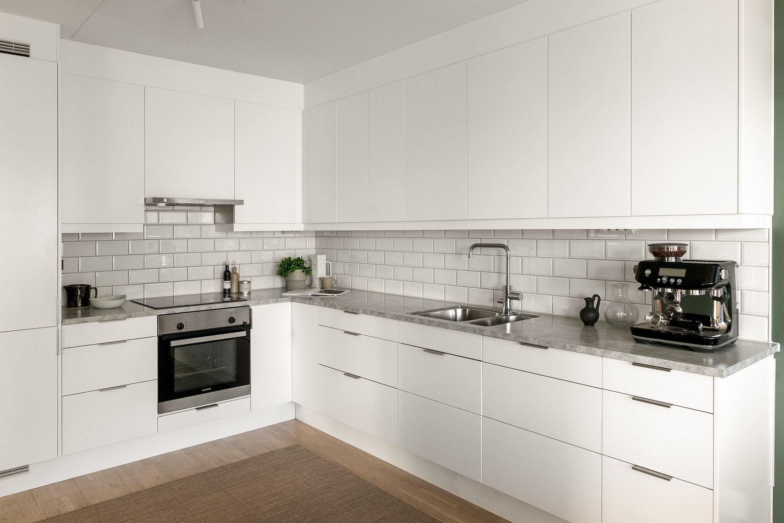 Kjøkkeninnredningen er utstyrt med stilrene glatte fronter, benkeplate i laminat med nedfelt kum i rustfritt stål og ledlys under overskap. Galleribilde