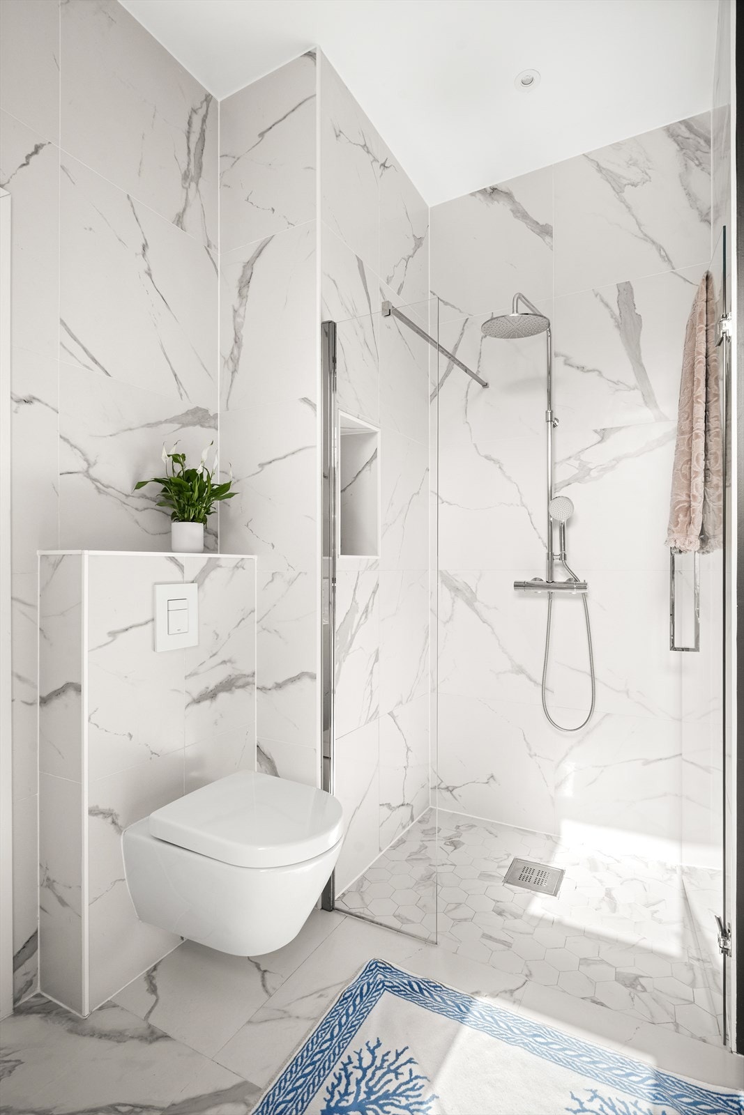 Badet har store, smakfulle fliser på vegger og gulv, med unntak av én kontrastvegg, og er utstyrt med downlights i himling samt behagelig gulvvarme. Galleribilde