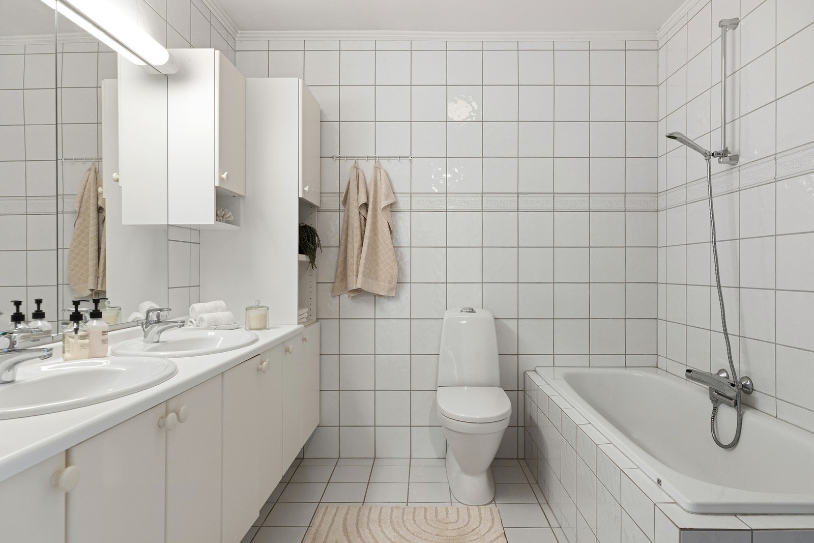 Badet er fra byggeår og har en romslig utforming med flere sanitærinstallasjoner. Innredningen består av to servanter, som gir god plass til daglig bruk og oppbevaring. Galleribilde