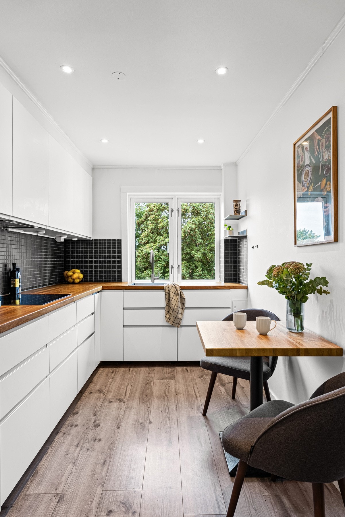 IKEA-kjøkken fra 2015 ligger i eget rom med laminatgulv og plass til spisebord. Innredningen består av hvite glatte fronter på skuffer og skapdører. Galleribilde