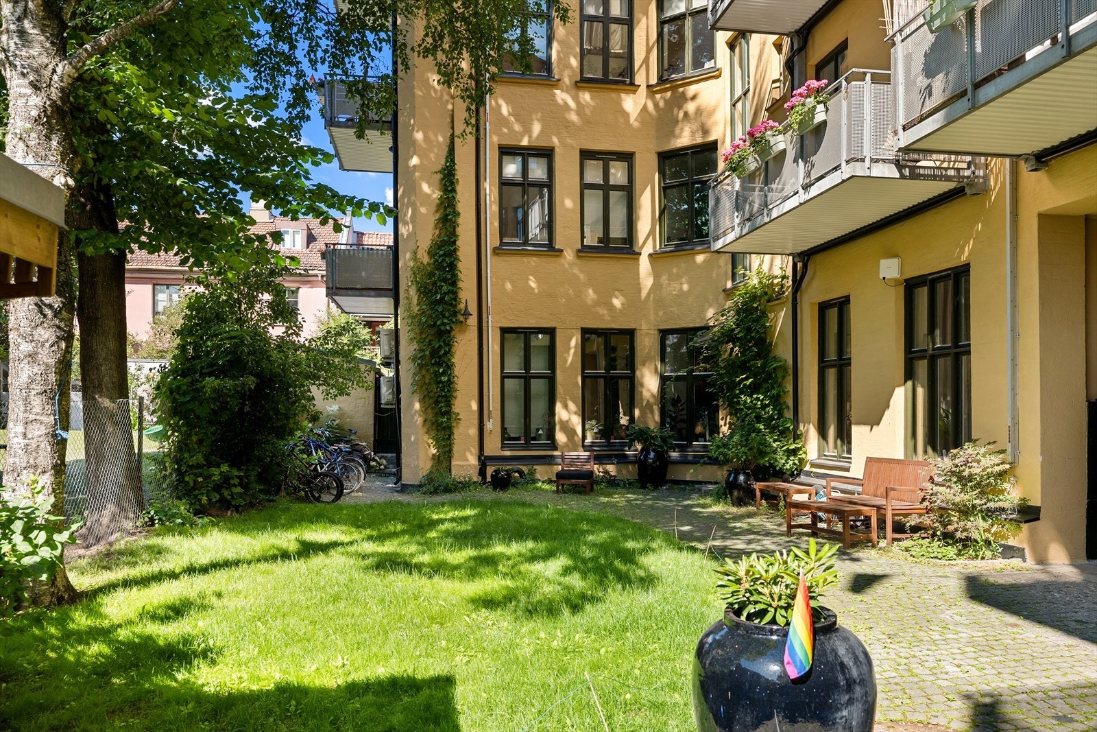Frodig og pent opparbeidet bakgård med felles sittegrupper, sykkelparkering og beplanting. Galleribilde