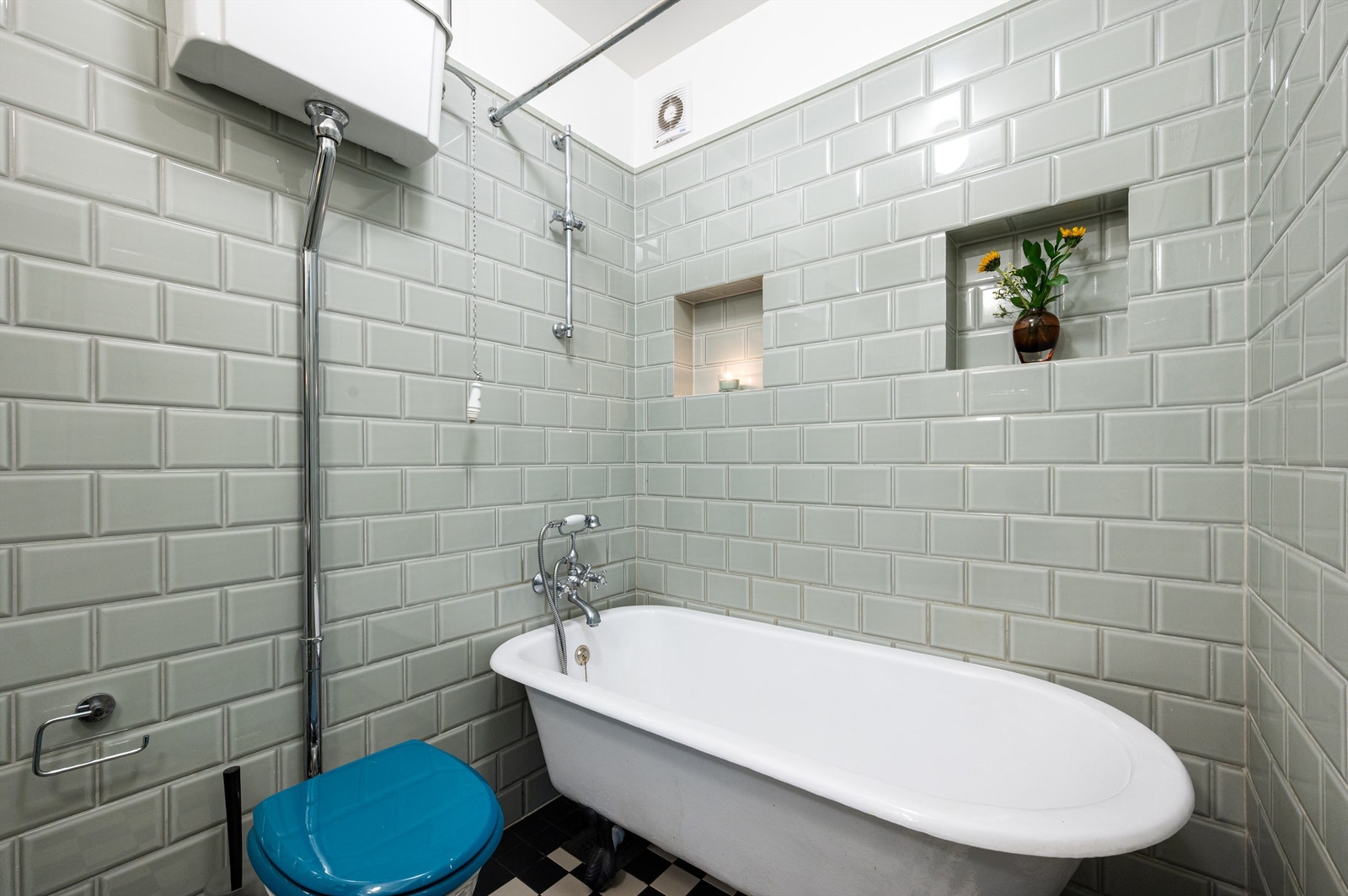 Badet er innredet med gulvstående toalett og badekar som er påkoblet hånddusj. Galleribilde