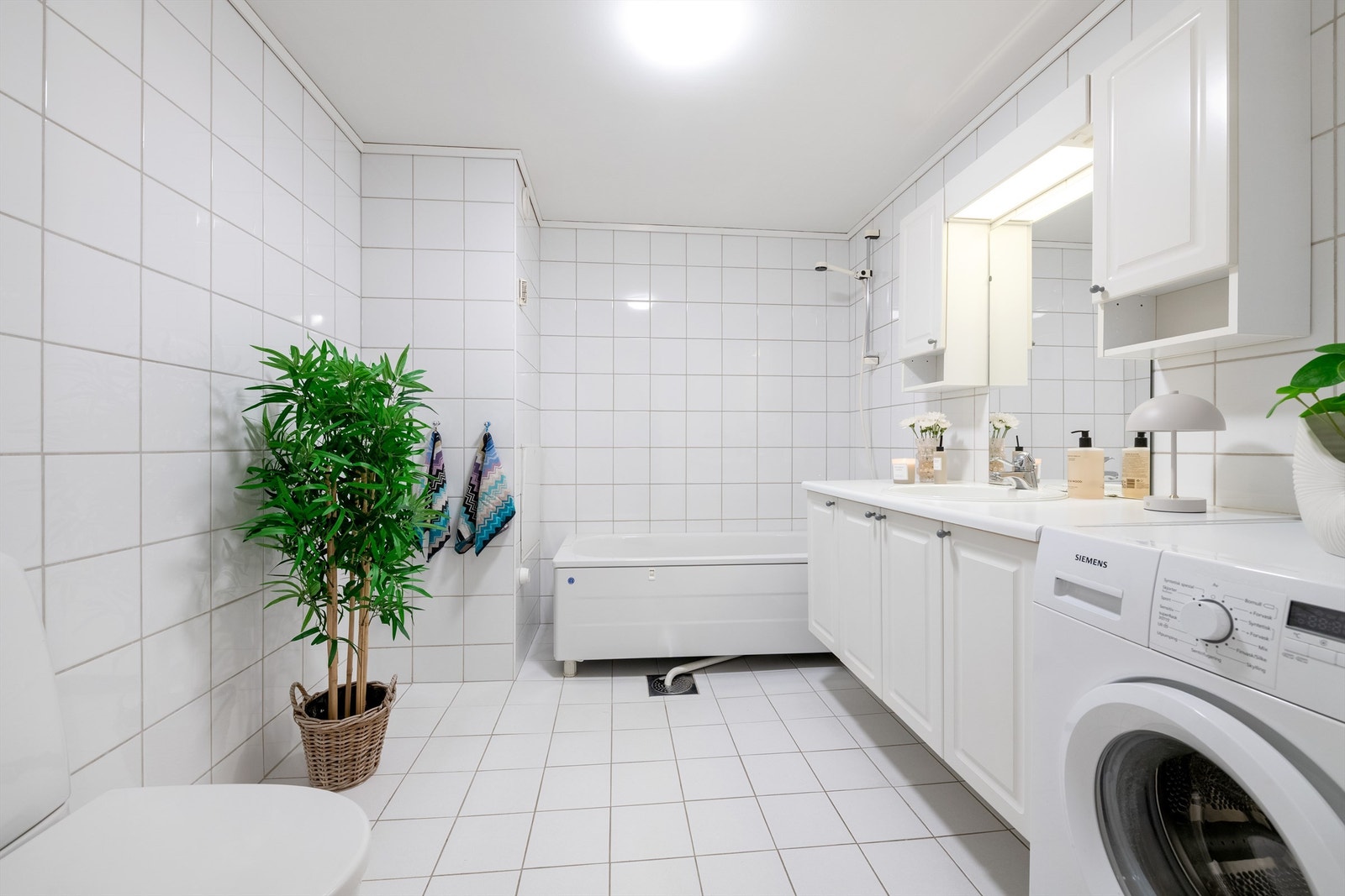 Badet er romslig og lyst med hvit baderomsinnredning og badekar. Fordelerskap for rør-i-rør system er plassert på bad. Galleribilde