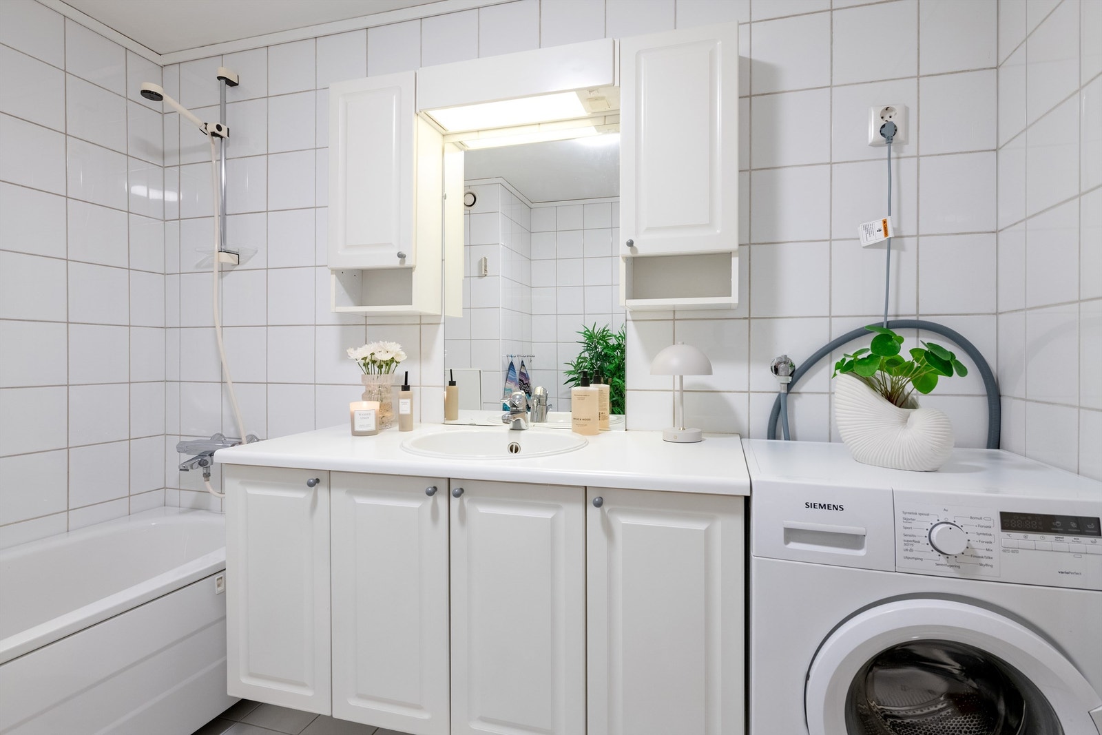 Hvit baderomsinnredning med god skapplass. Nedfelt vask og overskap med lys. Plass til vaskemaskin på badet. Varmekabler i gulv. Galleribilde