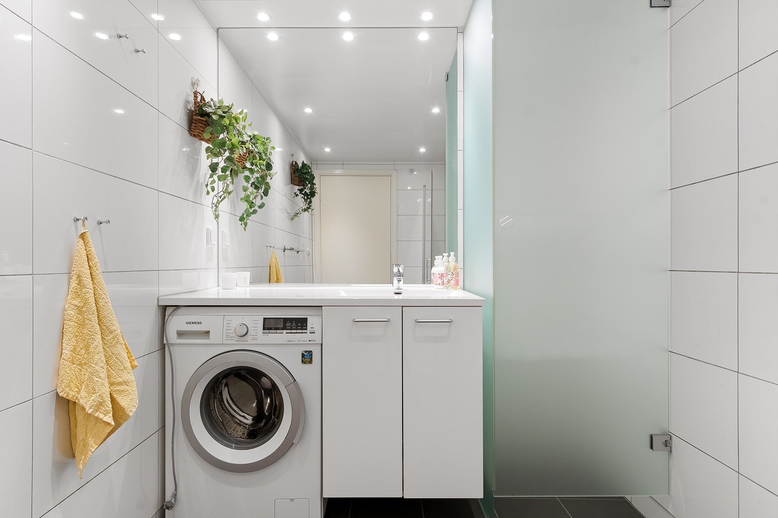 Badet er innredet med heldekkende servant på underskap med god oppbevaringsplass, speil, vegghengt toalett, dusjhjørne og opplegg for vaskemaskin. Galleribilde