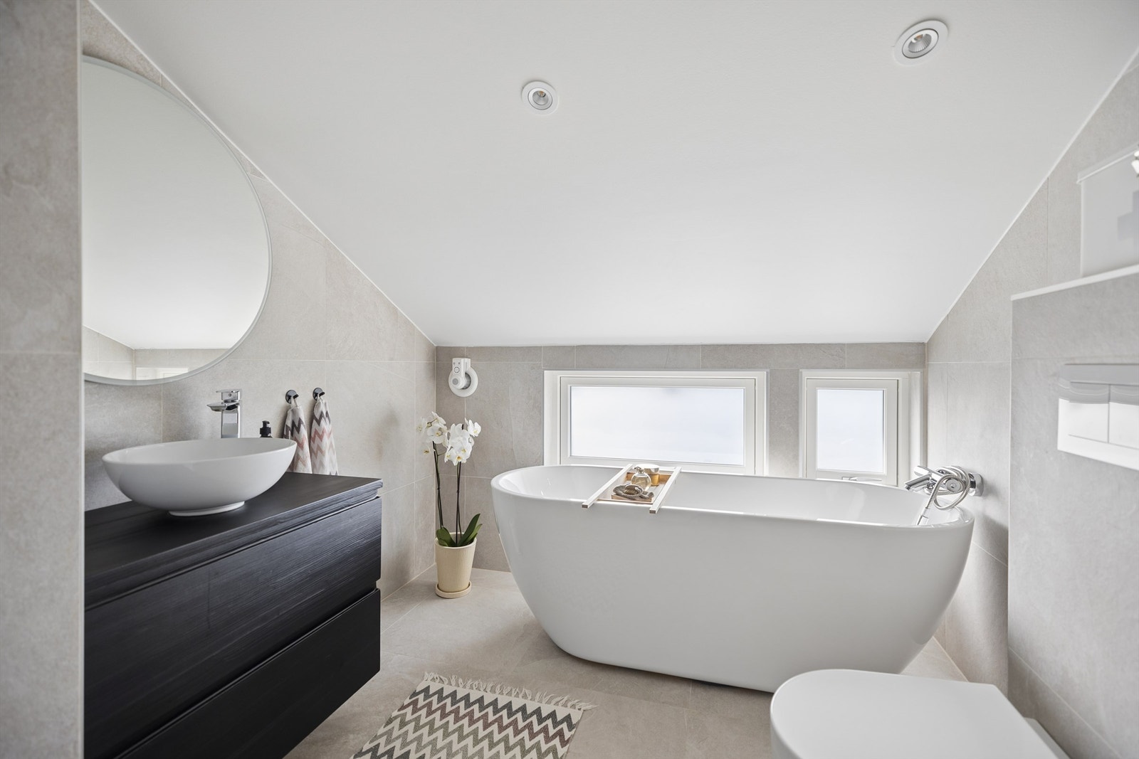 Lekkert, flislagt bad oppgradert i 2020. Badet fremstår som moderne og innbydende med badekar, dusjhjørne, servantinnredning og vegghengt toalett. Galleribilde