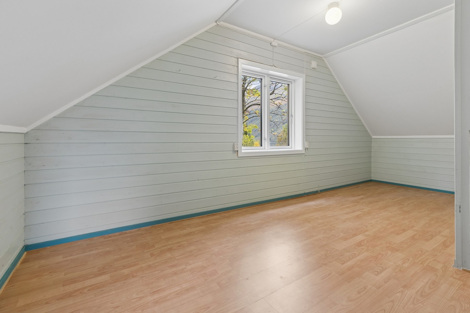 Loftsrom innredet med liggende panel og vindu som slipper inn dagslys. Galleribilde