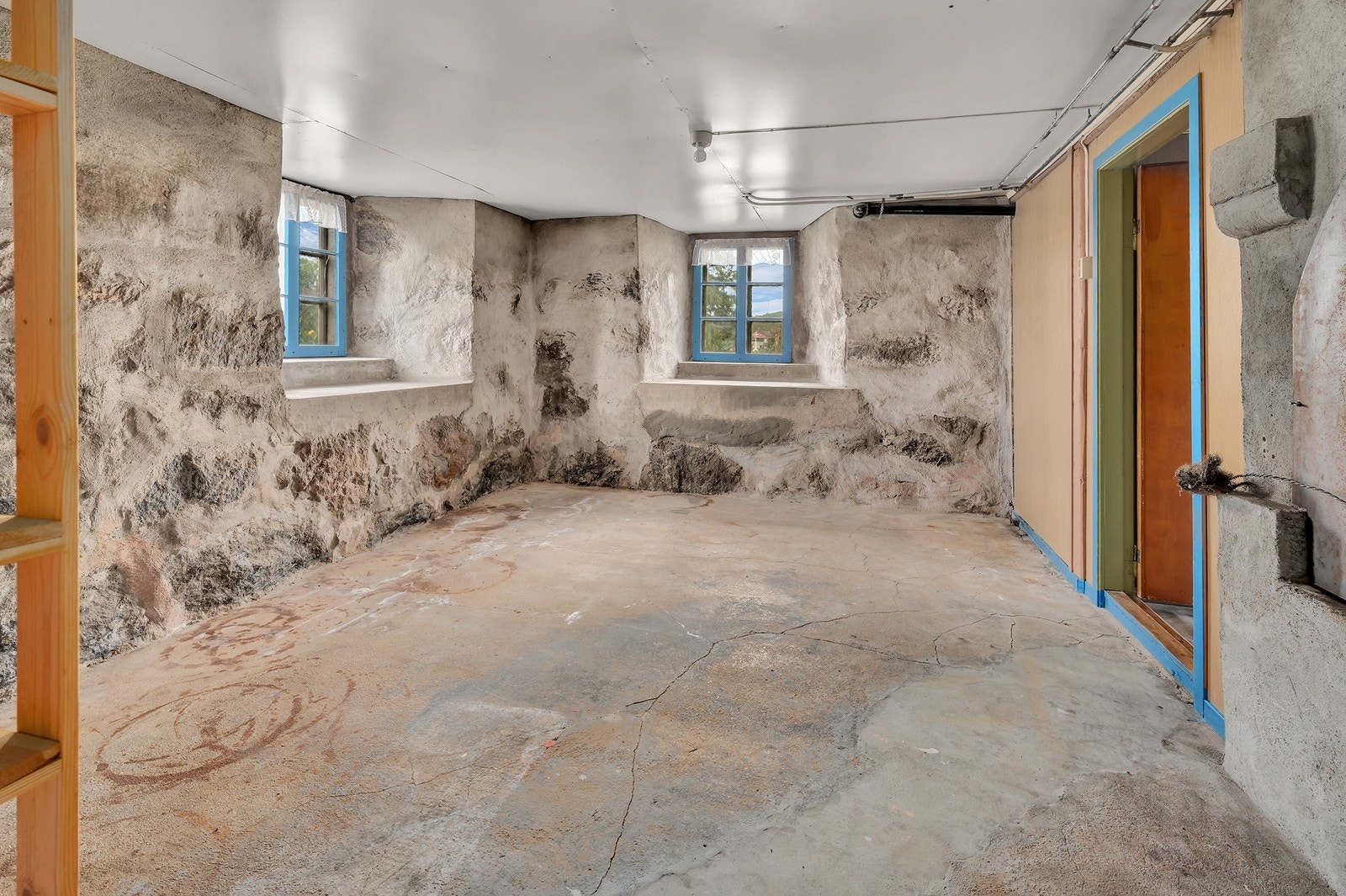 Kjellerrom med synlige natursteinsmurer og betonggulv. Galleribilde