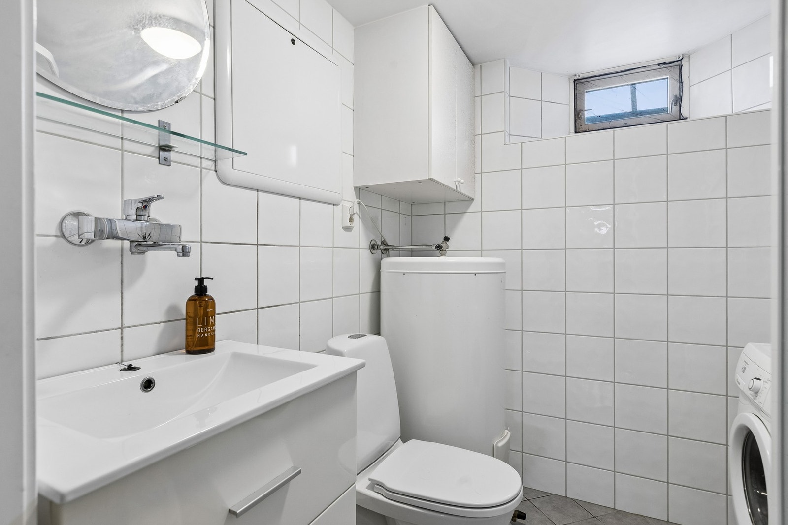 Badet er flislagt og utstyrt med gulvvarme, servantskap, WC, dusjkabinett, opplegg for vaskemaskin, varmtvannsbereder og mekanisk avtrekk. Galleribilde