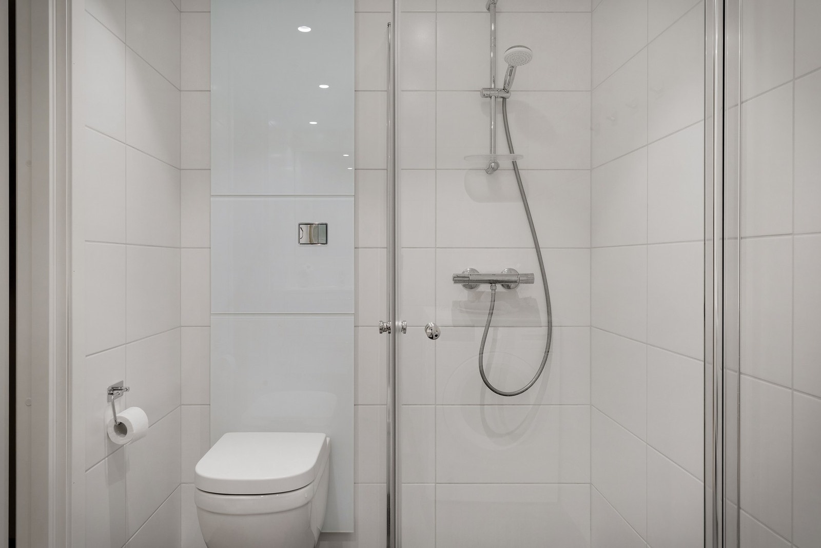 - Badet er innredet med stilrent baderomsmøblement som servant med underskap, speil, vegghengt toalett og dusj med foldedører i glass - Galleribilde
