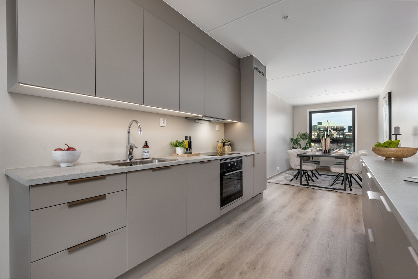 Smakfullt og tiltalende HTH type Stockholm i varm mokkafarge med integrerte hvitevarer som kombinert kjøl-/fryseskap, oppvaskmaskin og innebygget komfyr/koketopp. Galleribilde