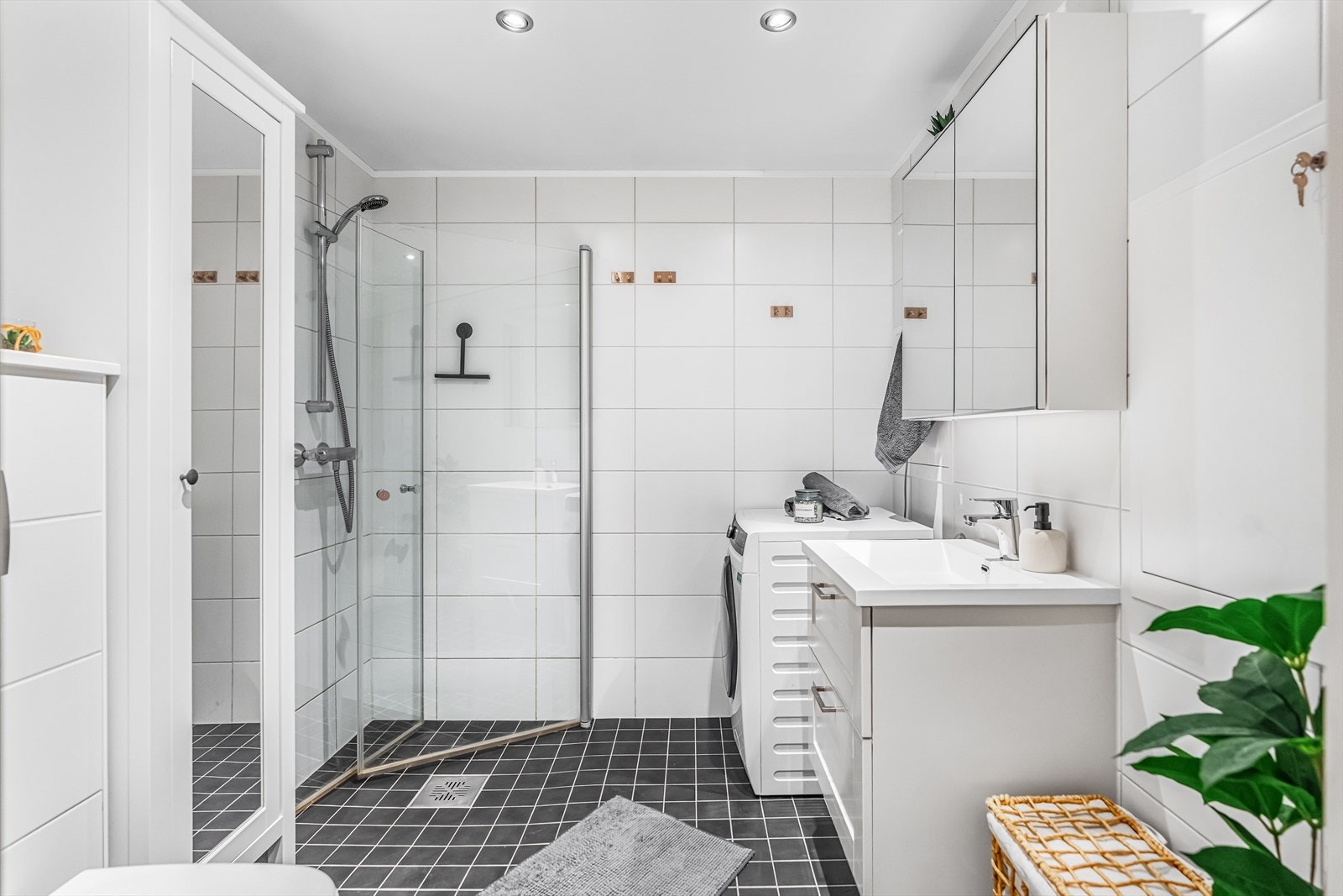 Badet har et helhetlig uttrykk med flislagte gulv og vegger, kombinert med slette overflater i himlingen. Galleribilde