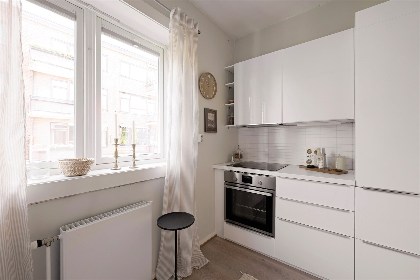 Innredningen har glatte fronter, laminat benkeplate med nedfelt kum i rustfritt stål og kjøkkenplater på veggen over benkeskapene. Galleribilde