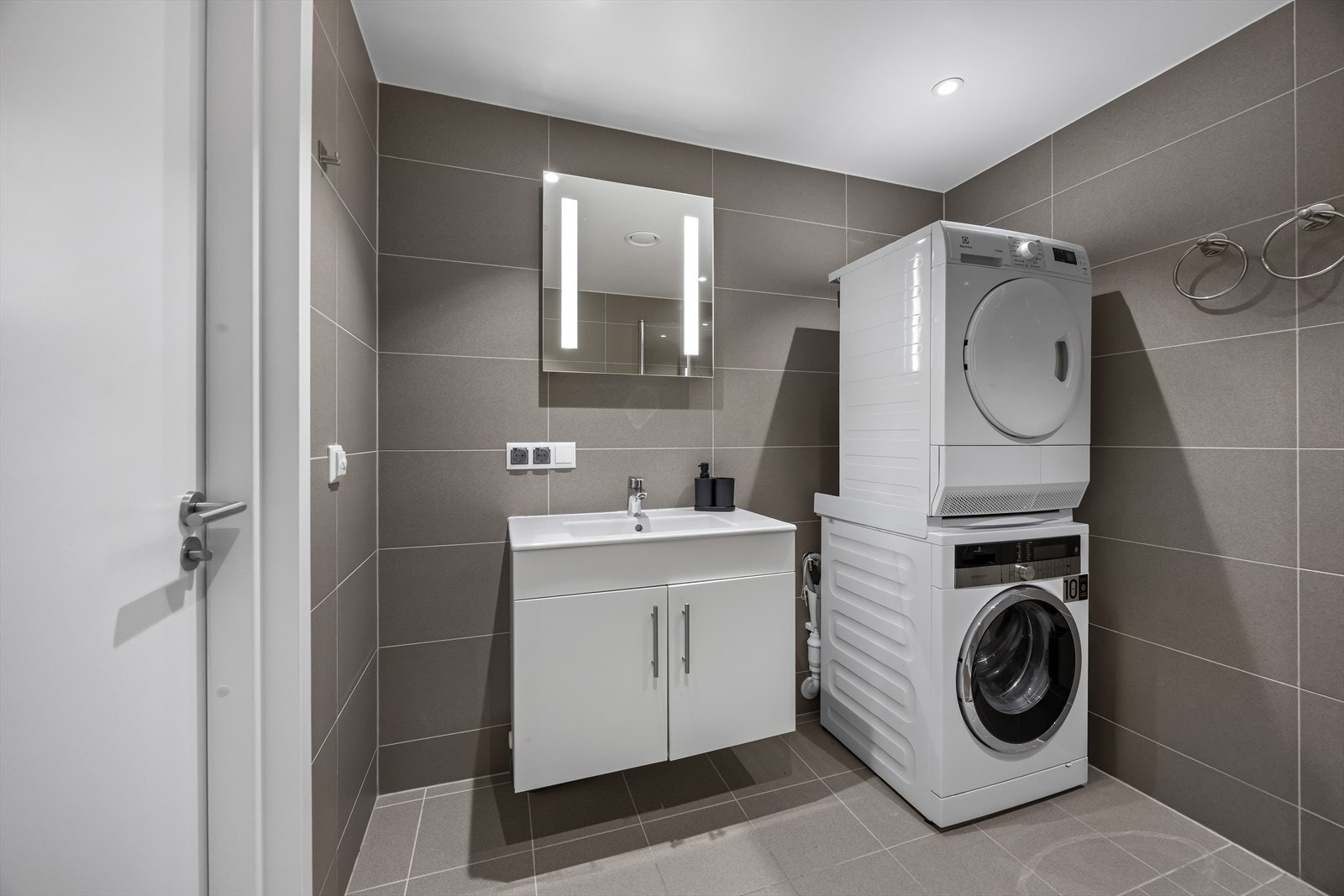 Badene er utstyrt med vegghengt toalett, servantinnredning, dusjhjørne med innfellbare glassdører samt speil med innfelt lys. Hovedbadet har i tillegg opplegg for vaskemaskin. Galleribilde