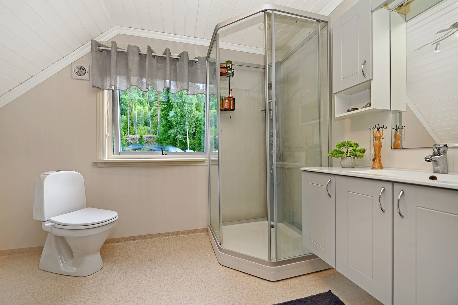 Badet har dusjkabinett, toalett og servant med underskap. Vinduer slipper inn naturlig lys. Galleribilde