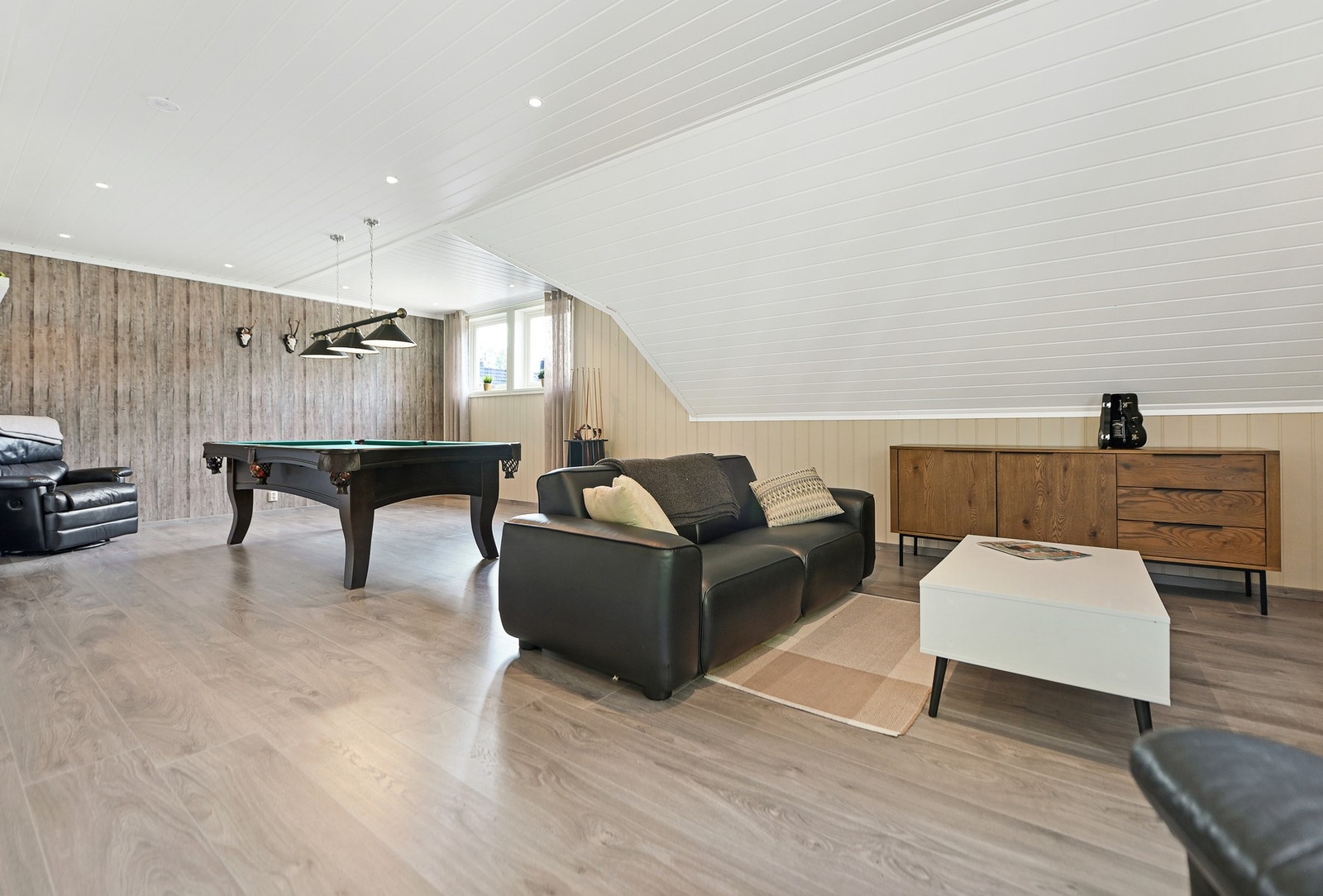 Loftet på uthuset: Romslig loftstue med skråtak, store vinduer og moderne belysning. Galleribilde