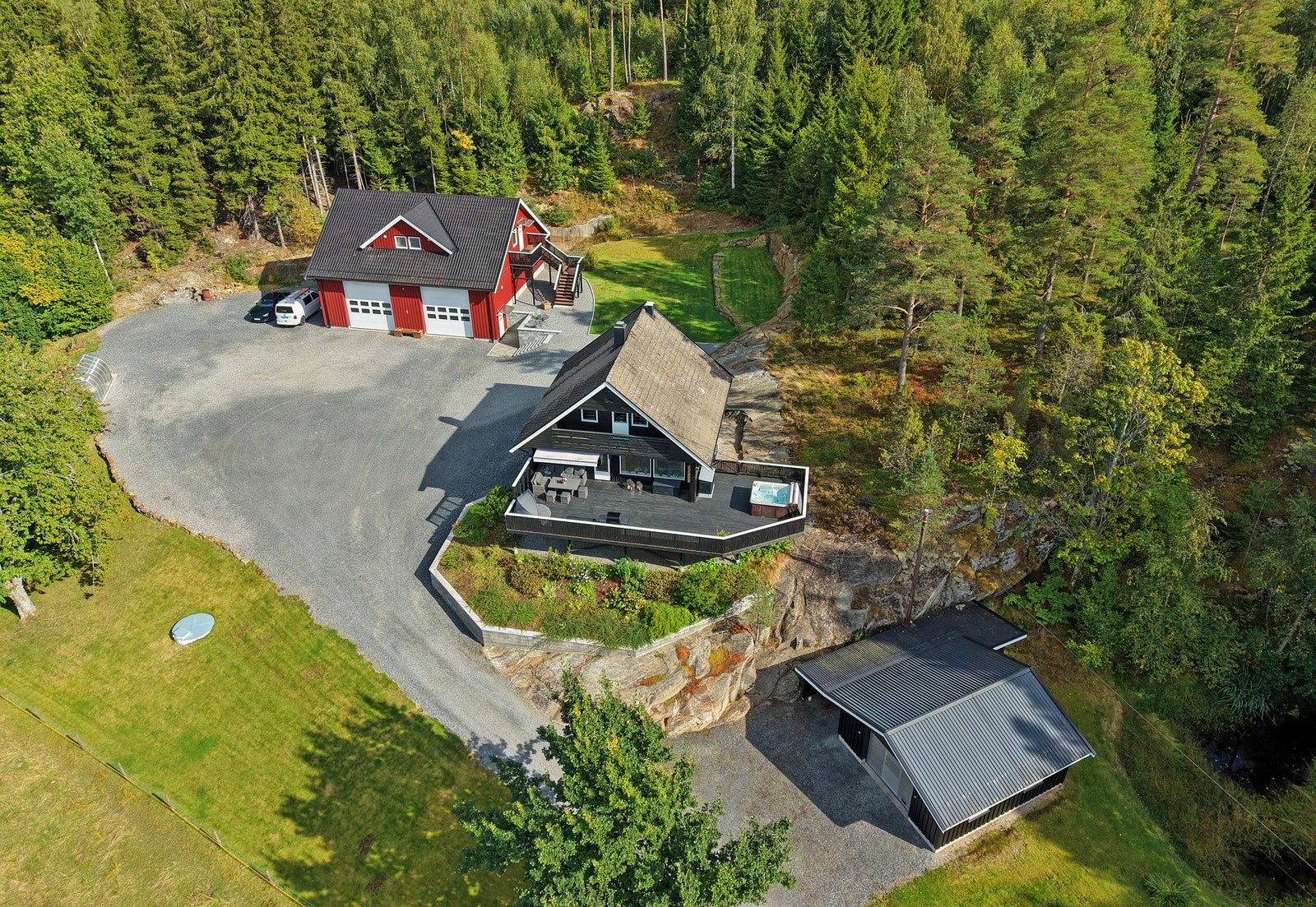 Boligen har en romslig tomt med stor gårdsplass og flere bygninger omgitt av skog og natur. Galleribilde