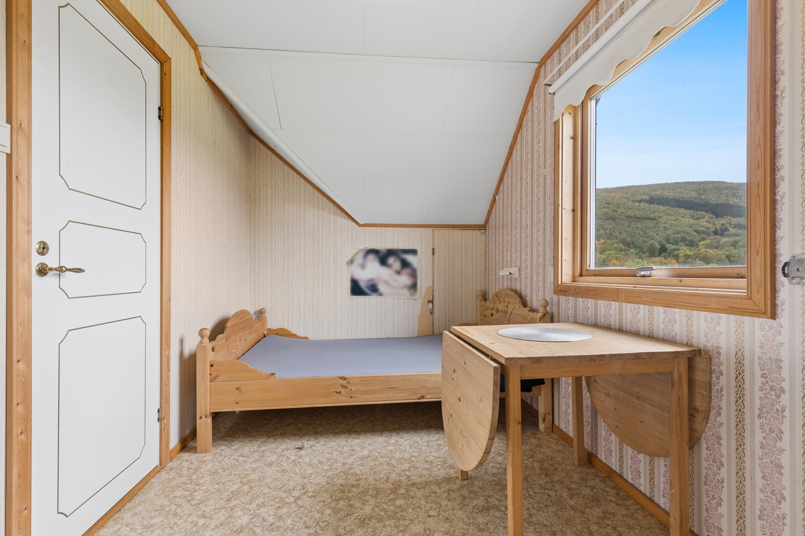 Soverom med skråtak og vindu mot naturskjønne omgivelser. Galleribilde