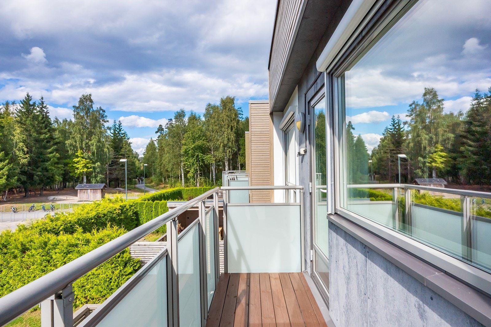 Fra vestvendt veranda er det åpen og luftig utsikt mot grøntområder, skogholt og omkringliggende bebyggelse. Galleribilde