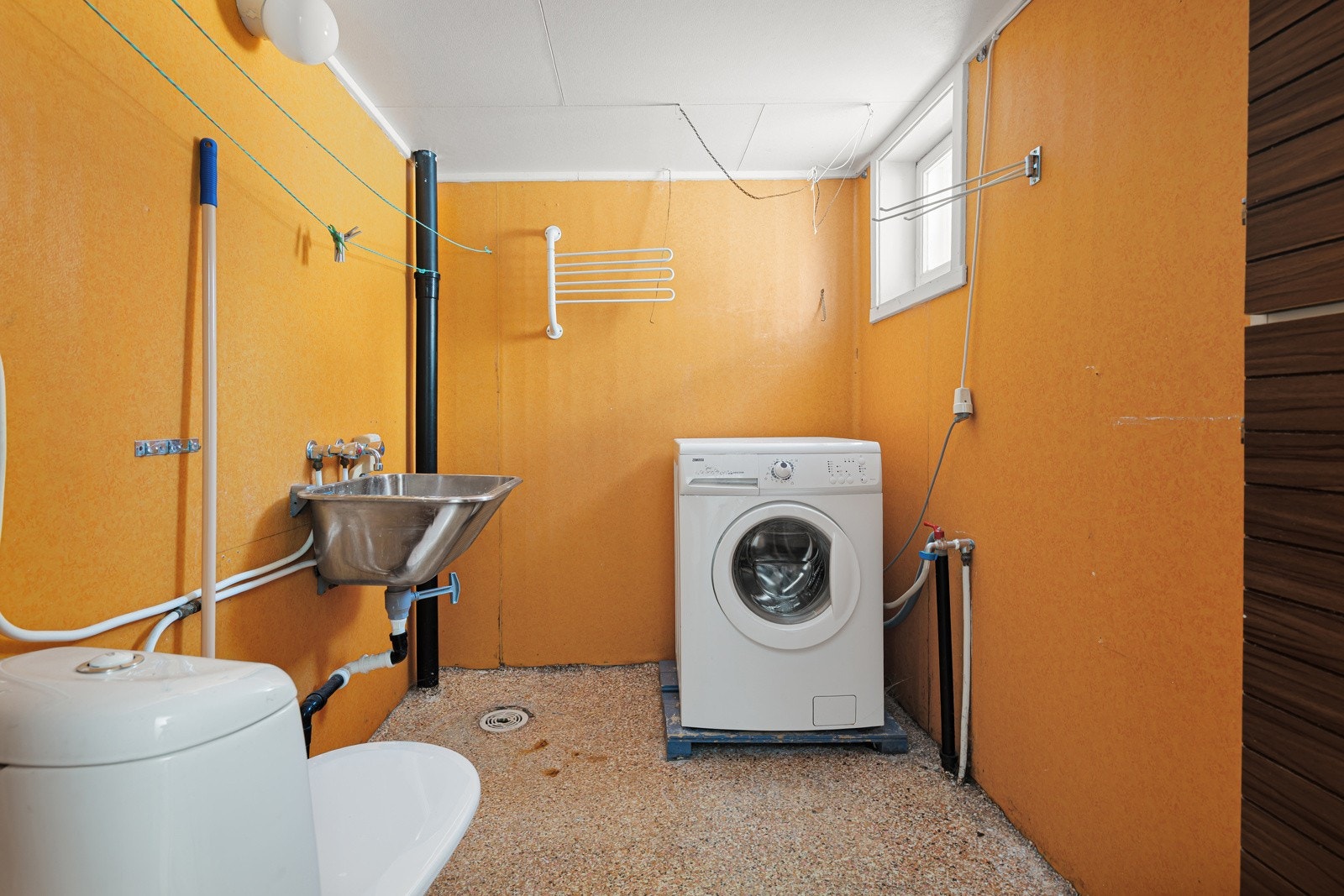 Vaskerom kjeller med malt betonggulv, skyllekum, wc og opplegg for vaskemaskin.