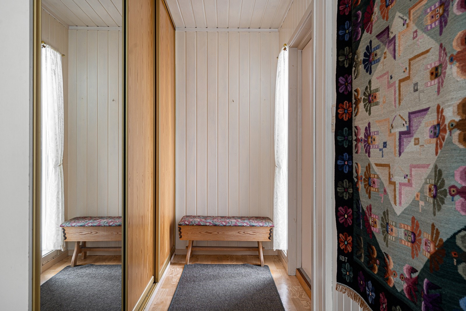 Velkommen inn! Entré med malte veggoverflater og en praktisk skyvedørsgarderobe med gode oppbevaringsmuligheter for yttertøy og sko