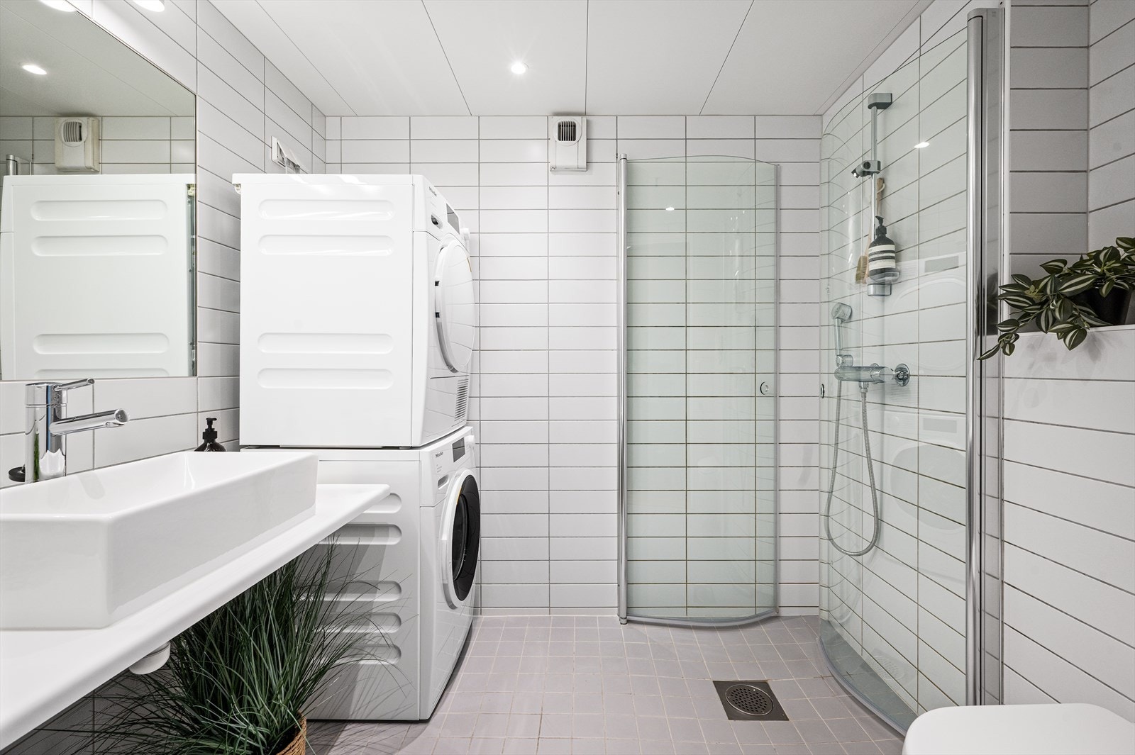 Romslig og lyst bad fra byggeåret med hvite, flislagte overflater, vannbåren gulvvarme og downlights i taket. Galleribilde