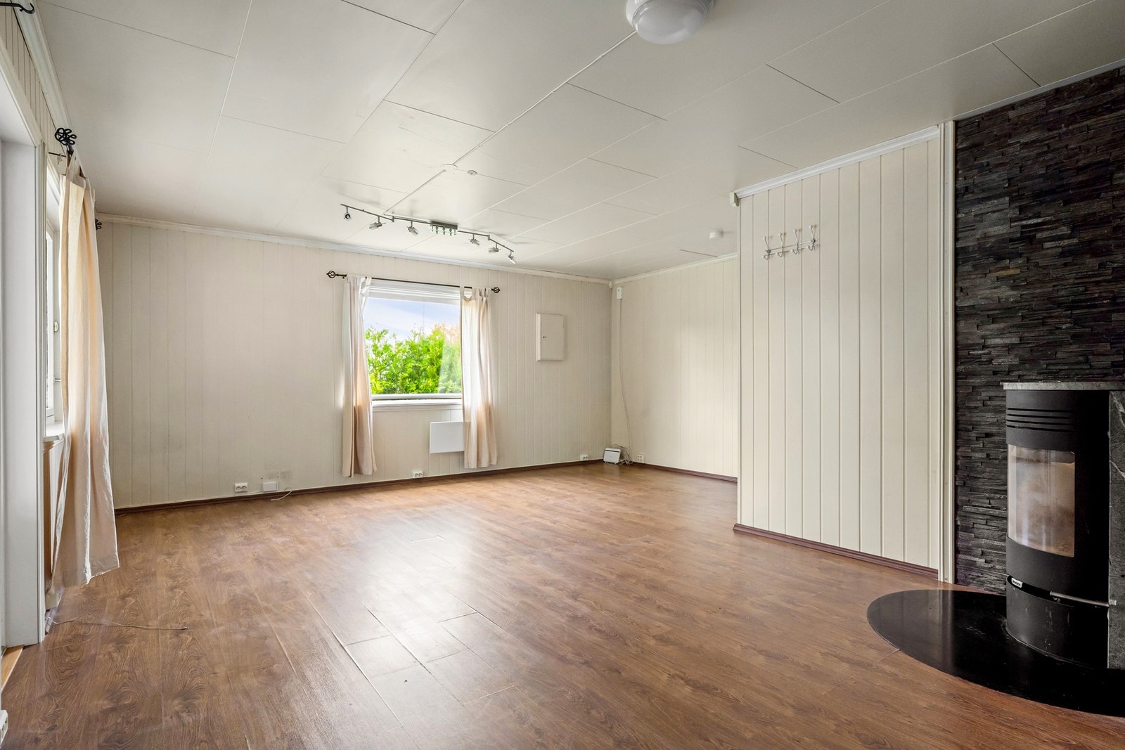 Romslig stue med store vindusflater, vedovn og utgang til uteområdet. Galleribilde
