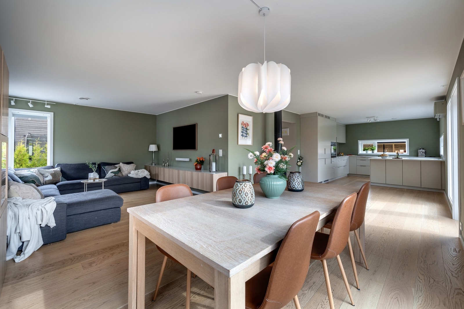 Innenfor entréen danner stuen og kjøkkenet et åpent og flott allrom, med rikelig lysinnslipp fra store vindusflater. Veggene er malt i moderne og tidløse farger, mens gulvet er belagt med parkett. Galleribilde