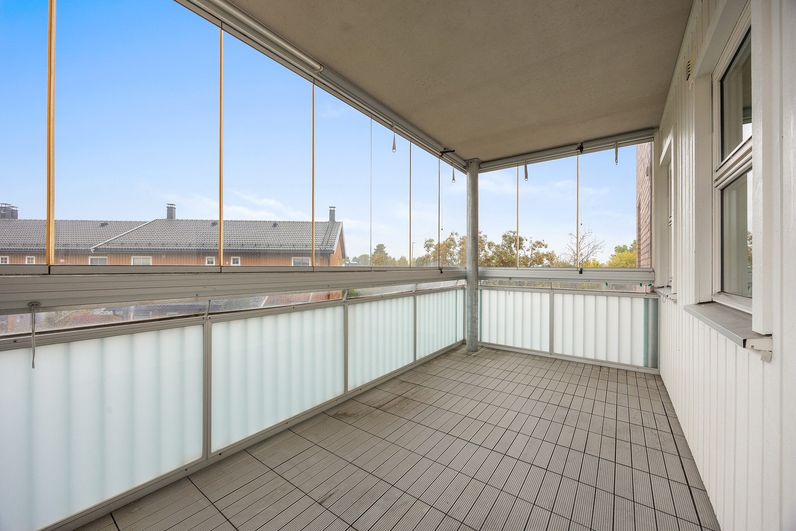 Innglasset balkong med skyvbare glassfelter og plastfliser på gulvet. Galleribilde