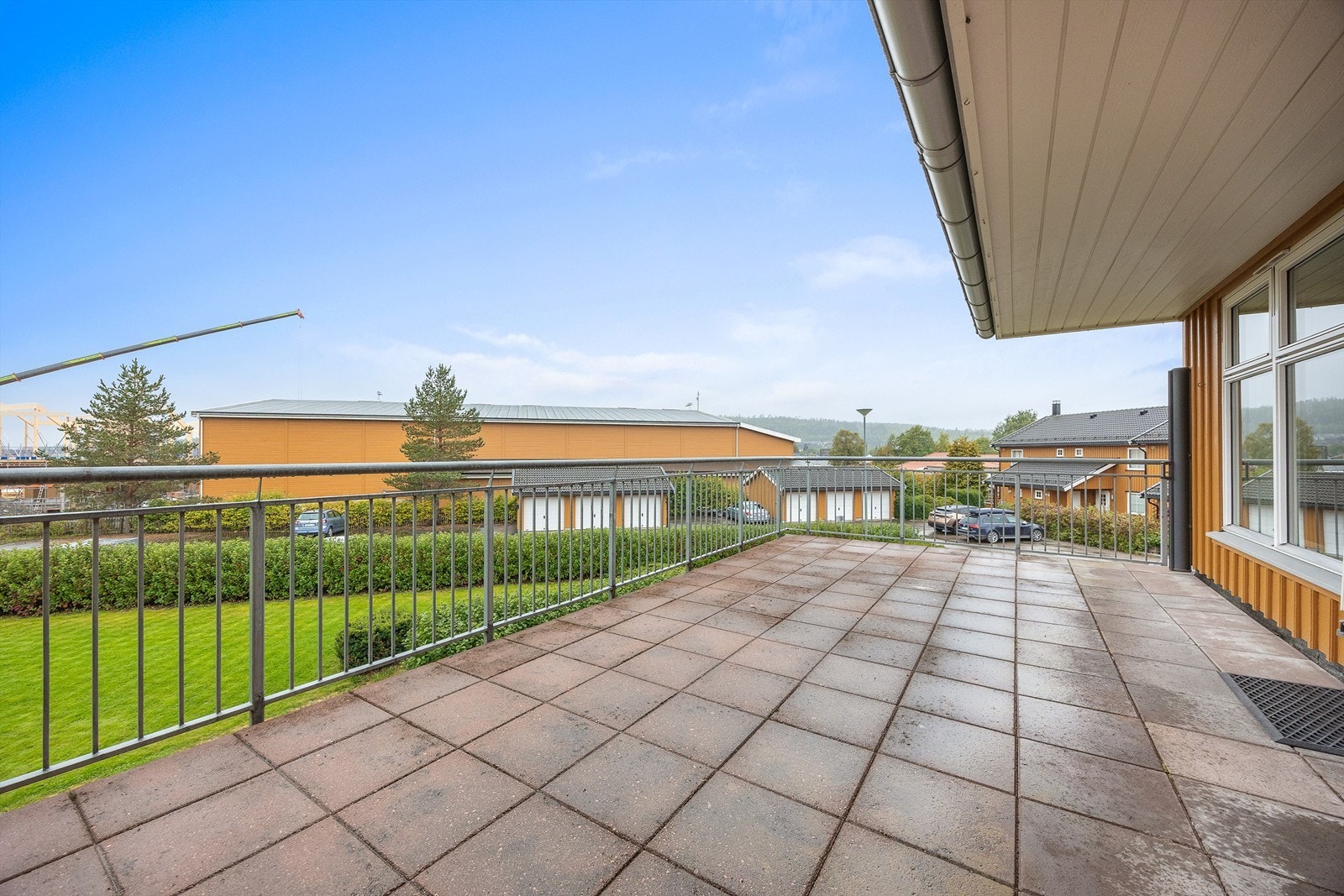 Terrassen har flislagt gulv, metallrekkverk og åpent utsyn. Galleribilde