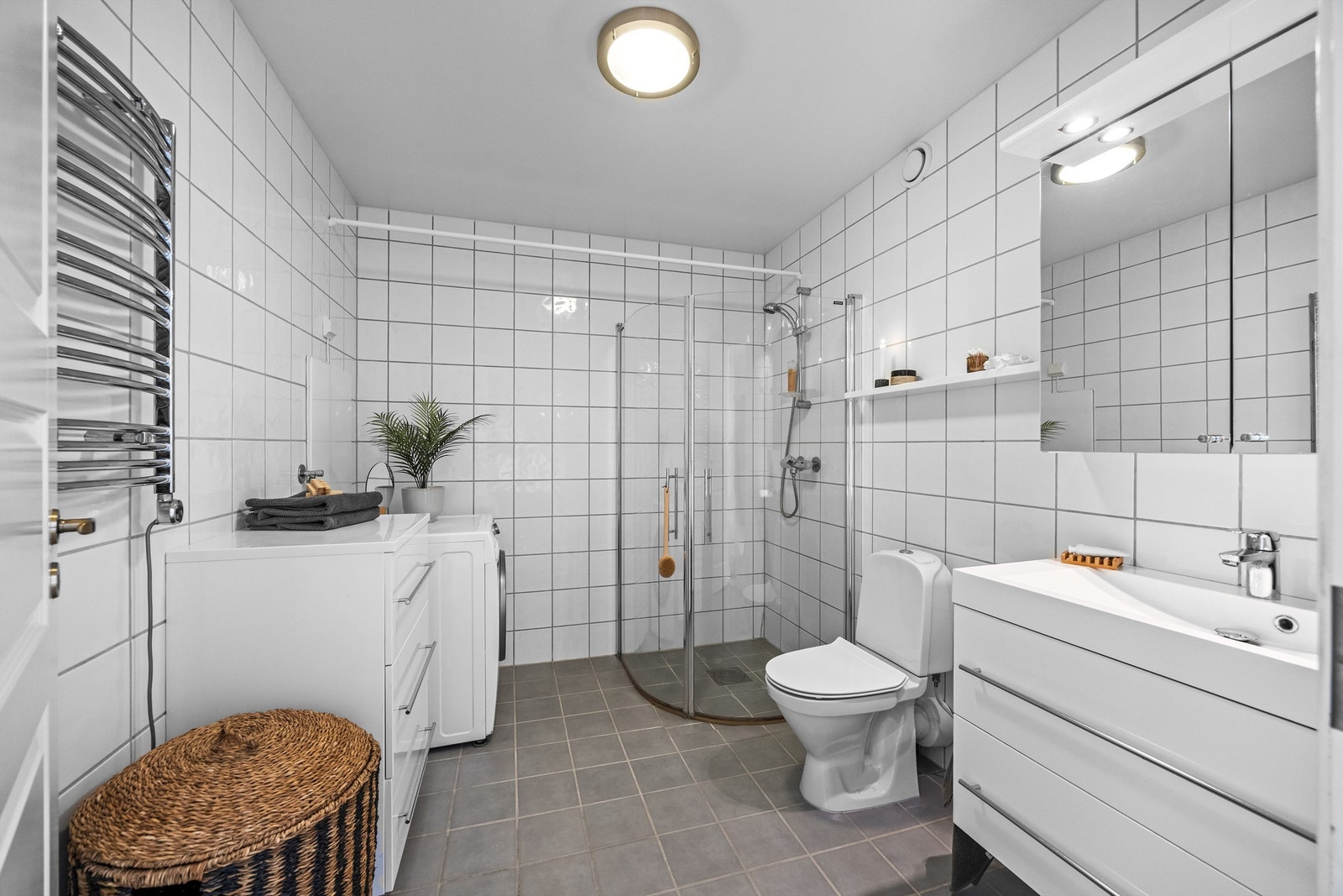 Stort bad, med fliser på vegger og gulv. Varmekabler og opplegg for vaskemaskin/tørketrommel. Galleribilde