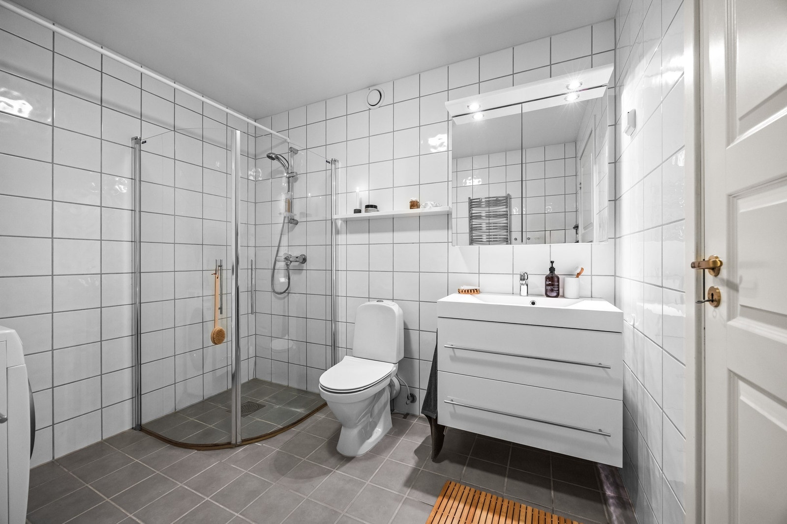 Badet har hvit glatt innredning med skuffer, speilskap og innfellbare dusjvegger. Galleribilde