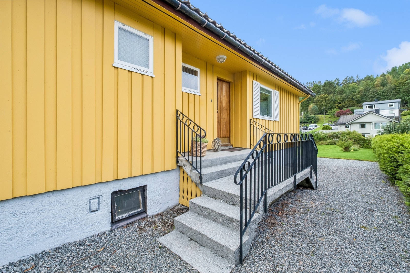 Adkomst til boligen via gruslagt gårdsplass og trapp til overbygget inngangsparti til hovedetasjen. Galleribilde