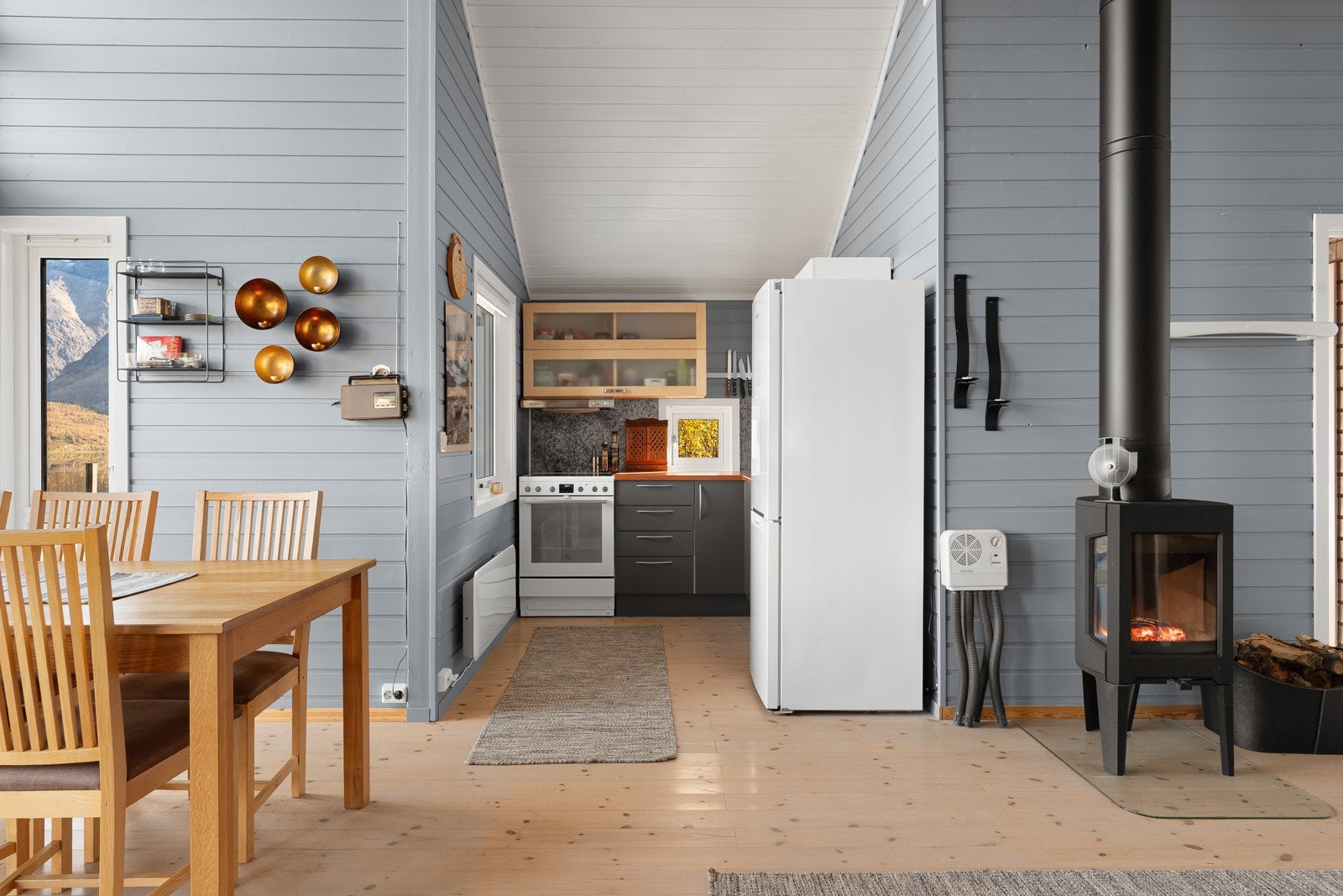 Stue og kjøkken ligger i åpen løsning og skaper et hyggelig samlingspunkt. Vedovnen gir god varme og hygge på kalde dager.