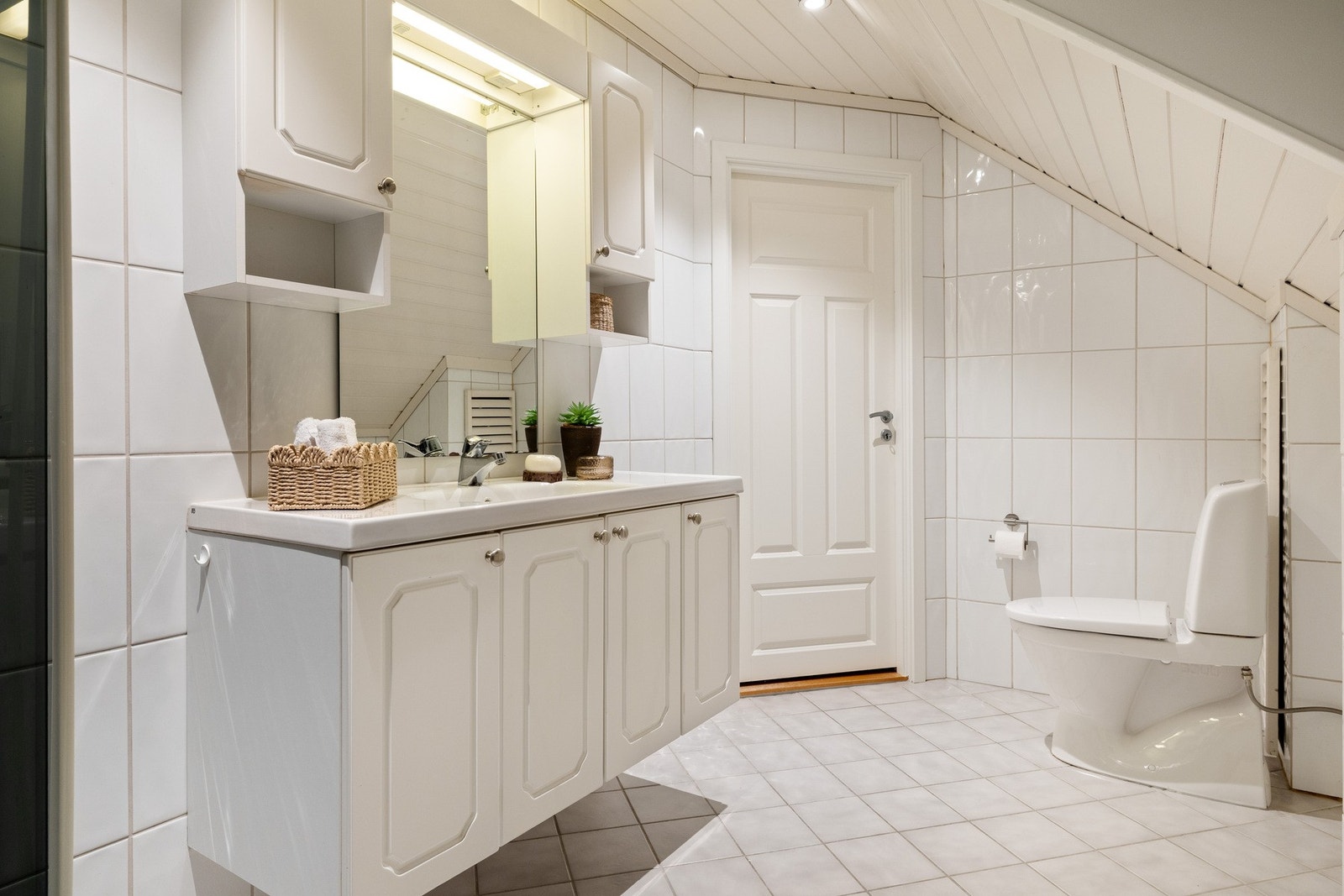 Badet er lyst og innredet med servant, toalett, dusjkabinett og opplegg for vaskemaskin. Galleribilde