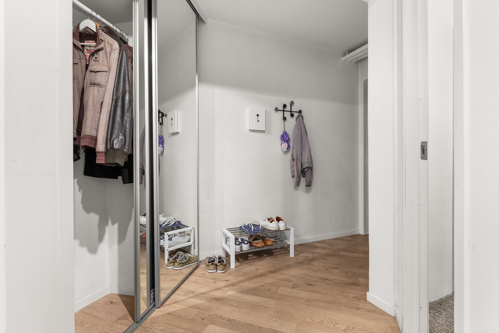 Romslig entré med skyvedørsgarderobe for effektiv oppbevaring av yttertøy. Galleribilde