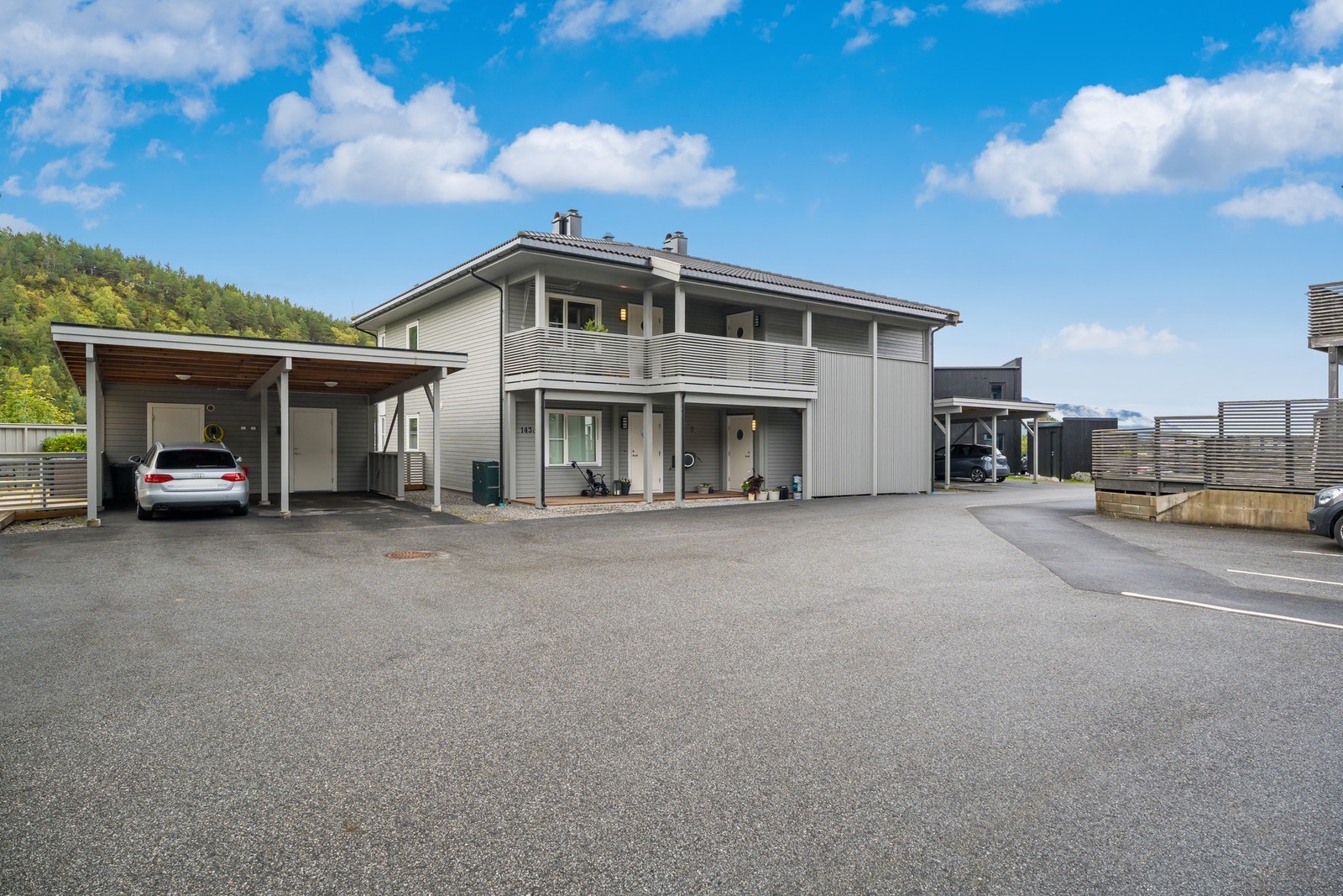 Parkering i carport som har romslig bod i bakkant, asfalterte og flate fellesområder. Galleribilde