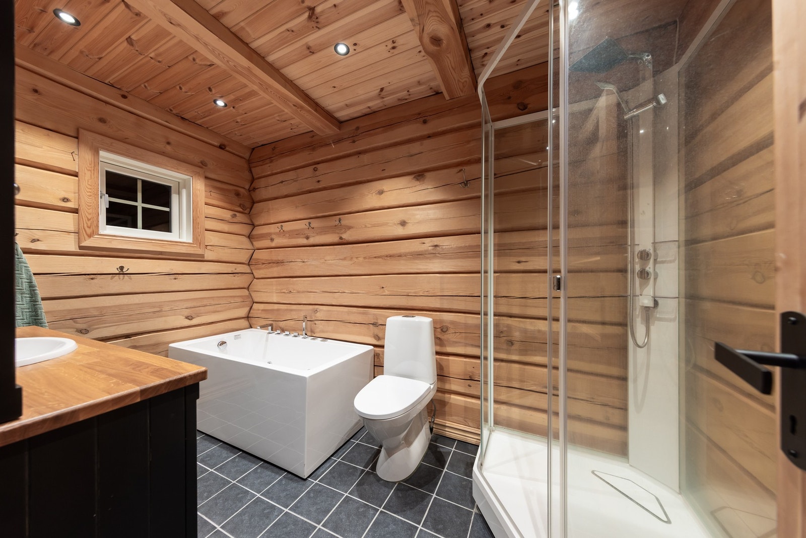 Videre har badet laftede tømmervegger og grå fliser med gulvvarme. Galleribilde