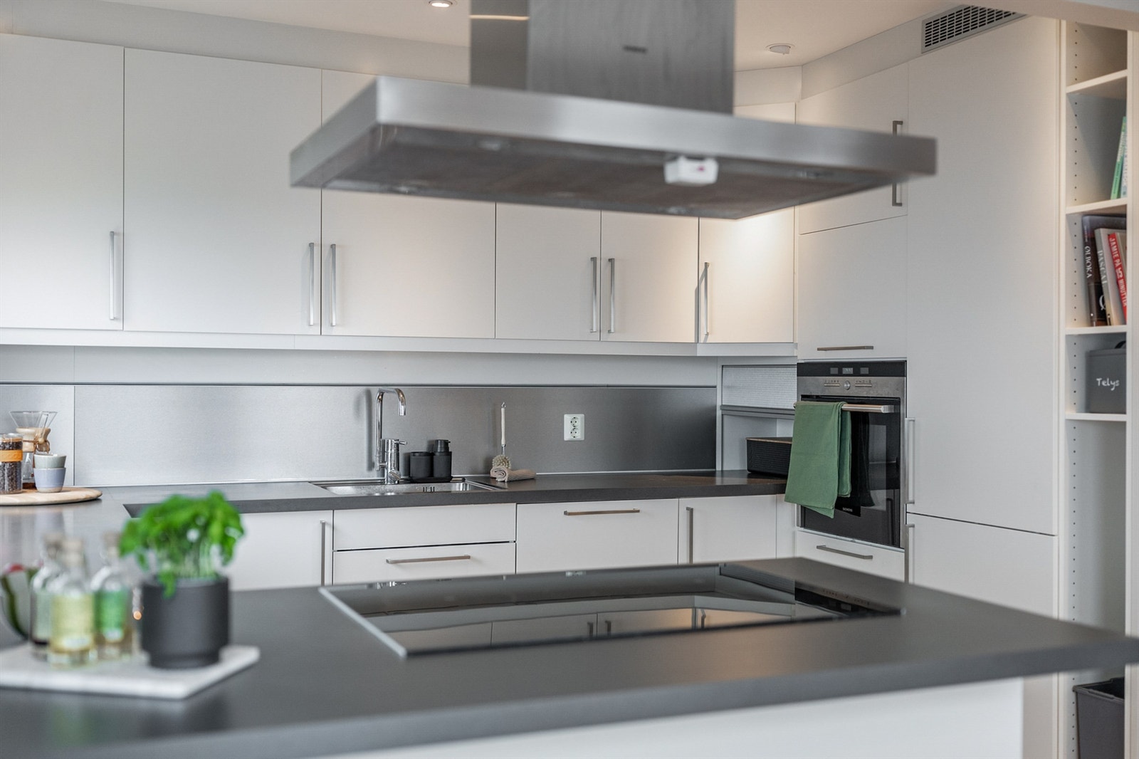 Nedfelt platetopp fra Siemens. Takhengt ventilator. Det er montert metallplate på vegg bak kjøkkenvask Galleribilde
