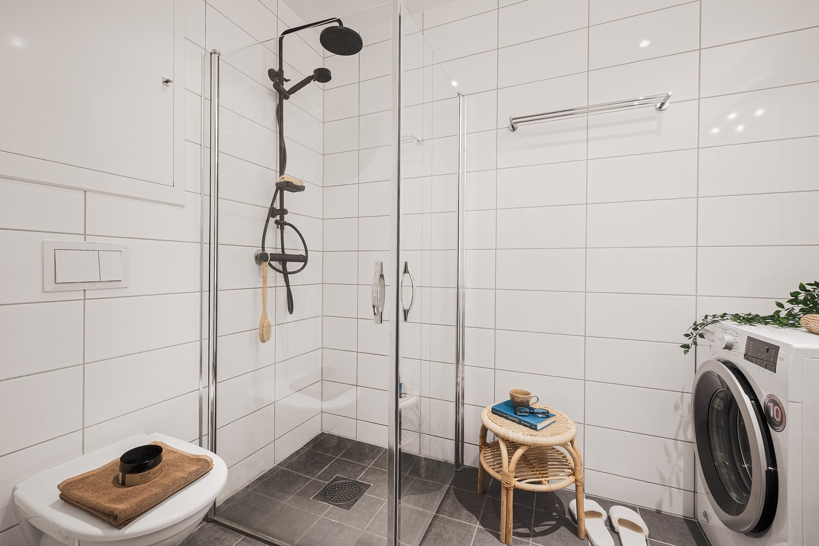 Badet er innredet med nedfelt servant med møblement, veggmontert toalett, dusjhjørne, og opplegg for vaskemaskin. Galleribilde