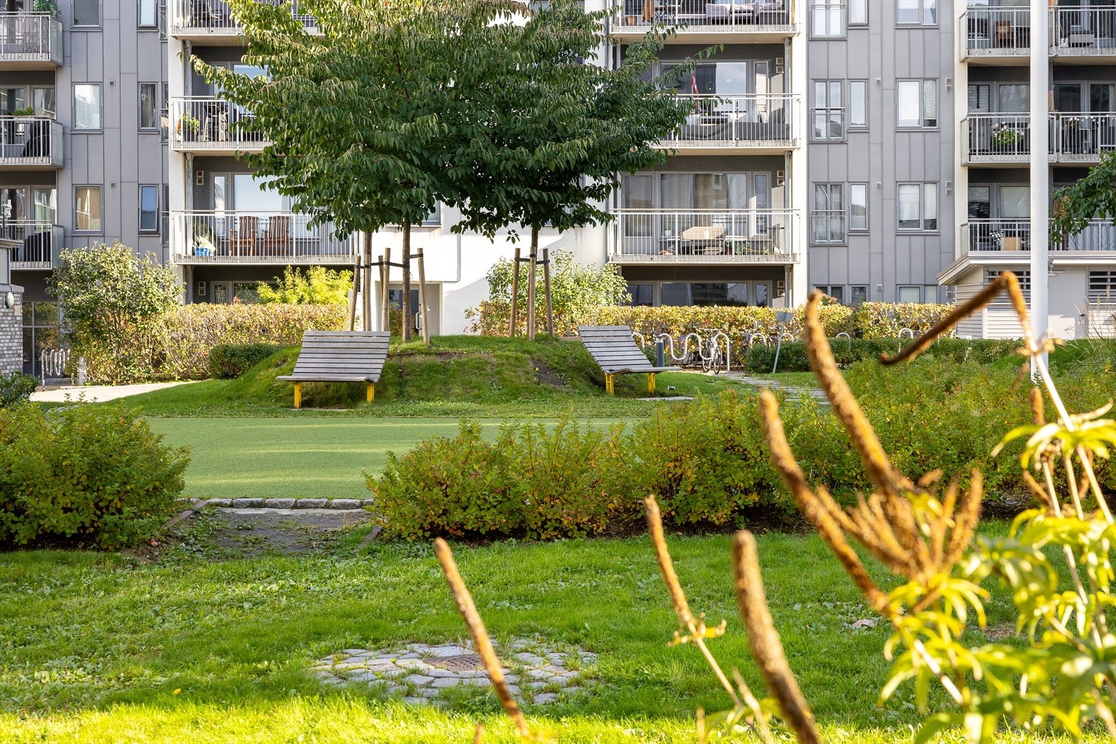 Bakgården i sameiet er frodig med grøntarealer og sittegrupper Galleribilde