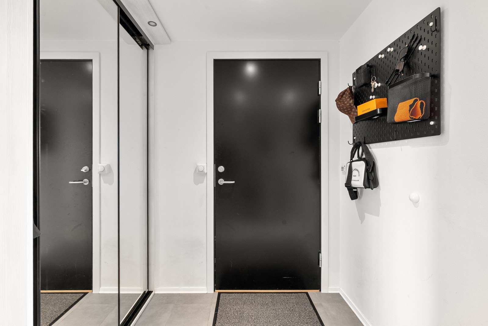 Flislagt entrè med skyvedørsgarderobe som sikrer godt med oppbevaringsplass for yttertøyet.
