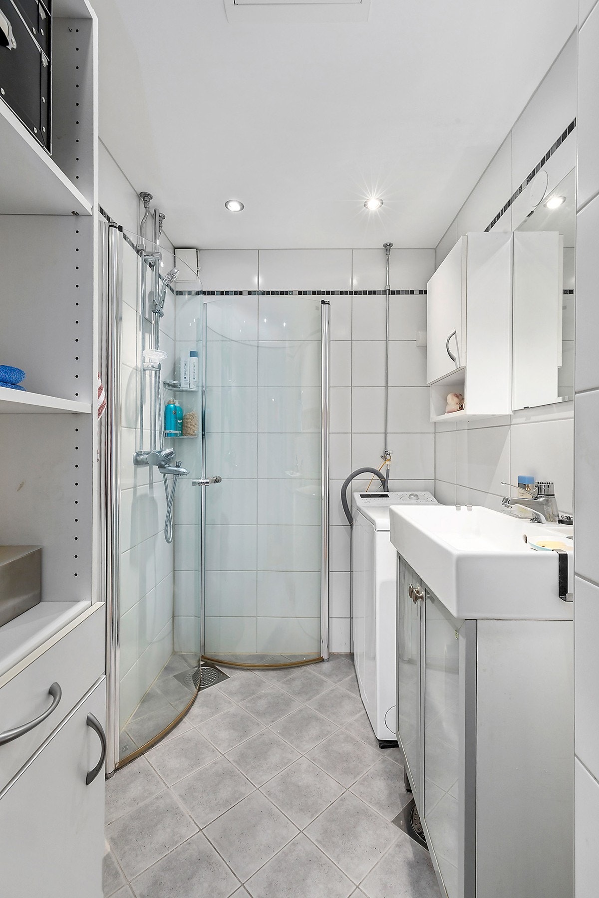 Badet fremstår som lyst og velholdt og er utstyrt med dusj med buede inn- og utadslående dusjdører, servant med underskap og speil, samt veggskap. Vaskemaskin medfølger. Galleribilde